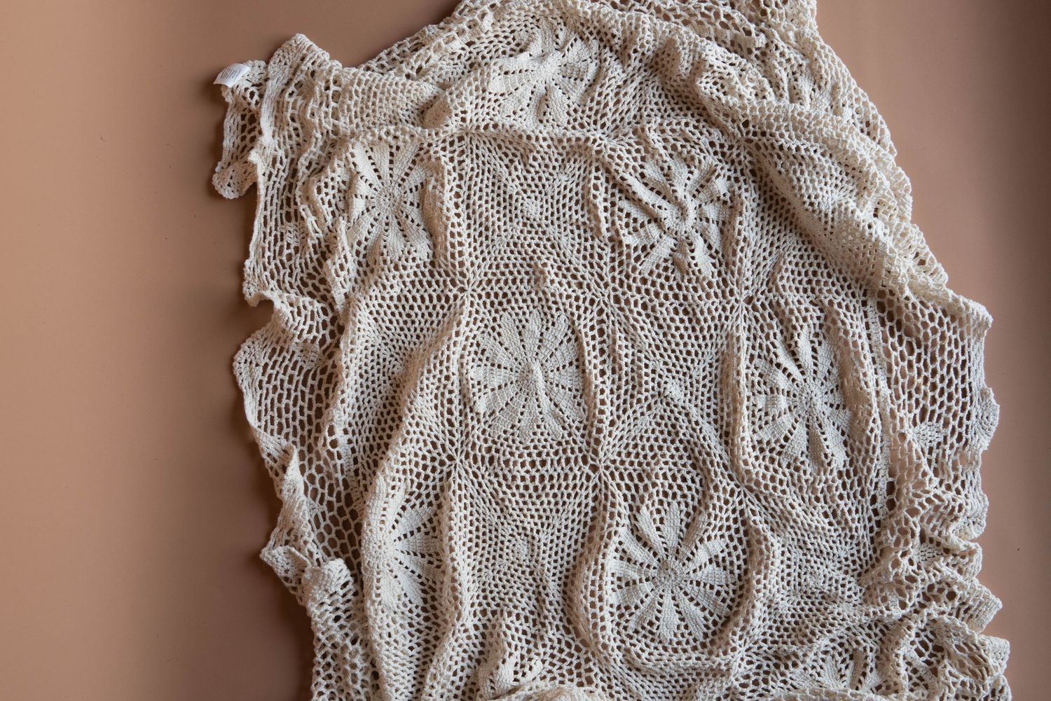 Vintage white lace fabric with delicate floral pattern shown in detail.