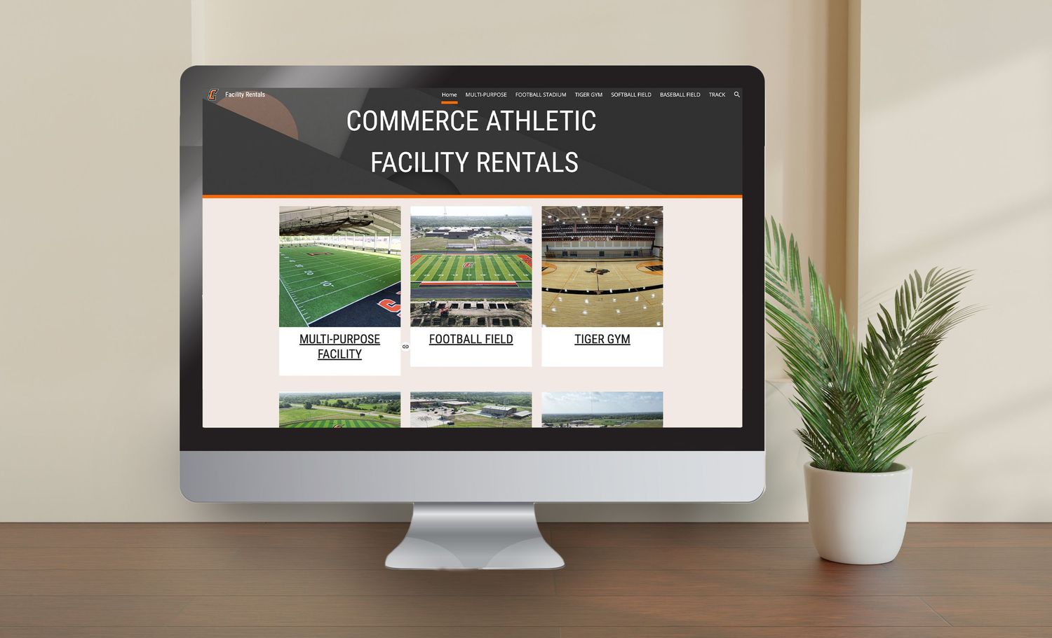 A desktop computer displaying a website for Commerce Athletic facility rentals with sports field images on the screen.
