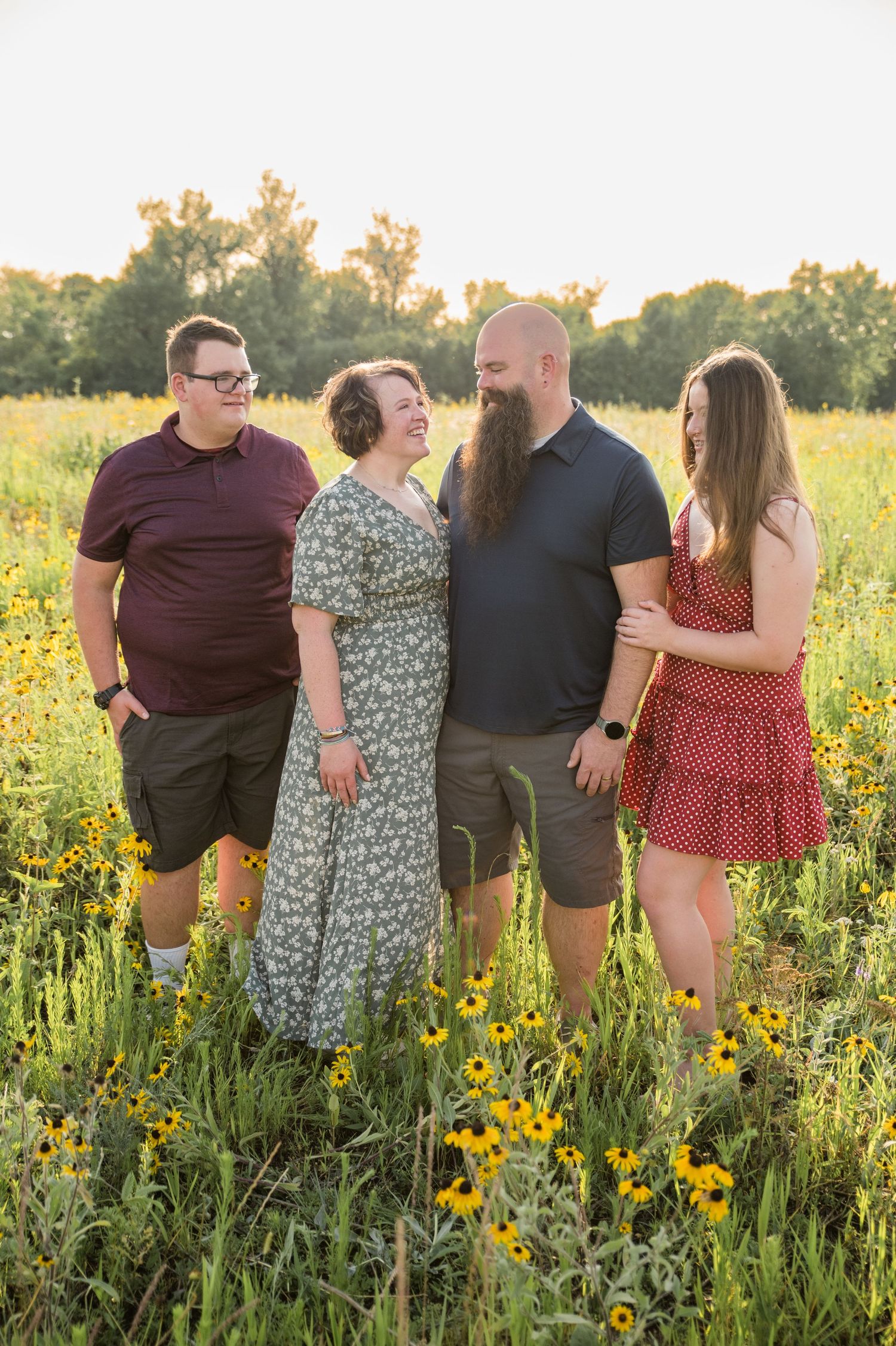 A group stands together in a summer meadow filled with yellow wildflowers during golden hour sunset.