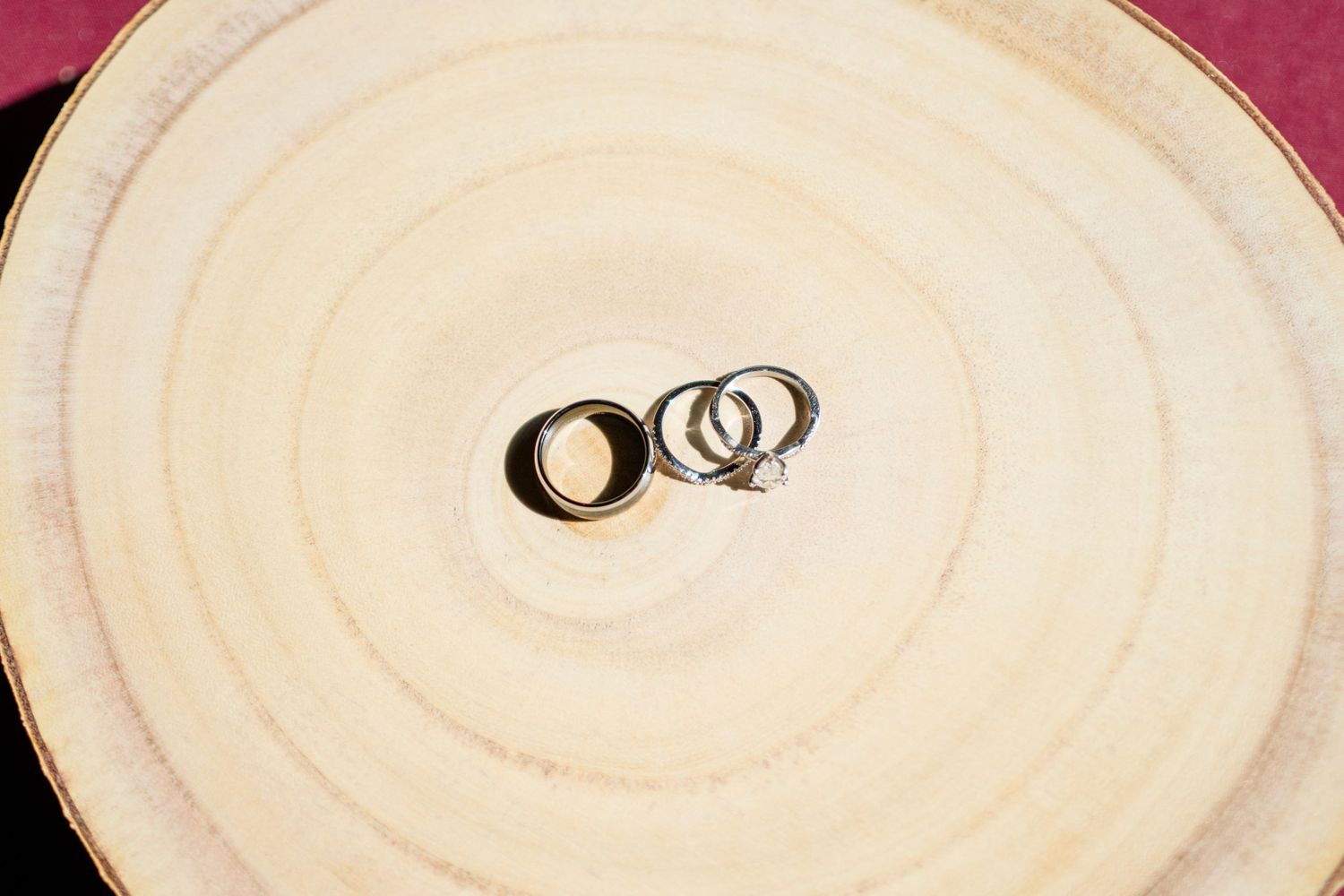 Wedding rings casting shadows on a white ceramic plate with circular design pattern.