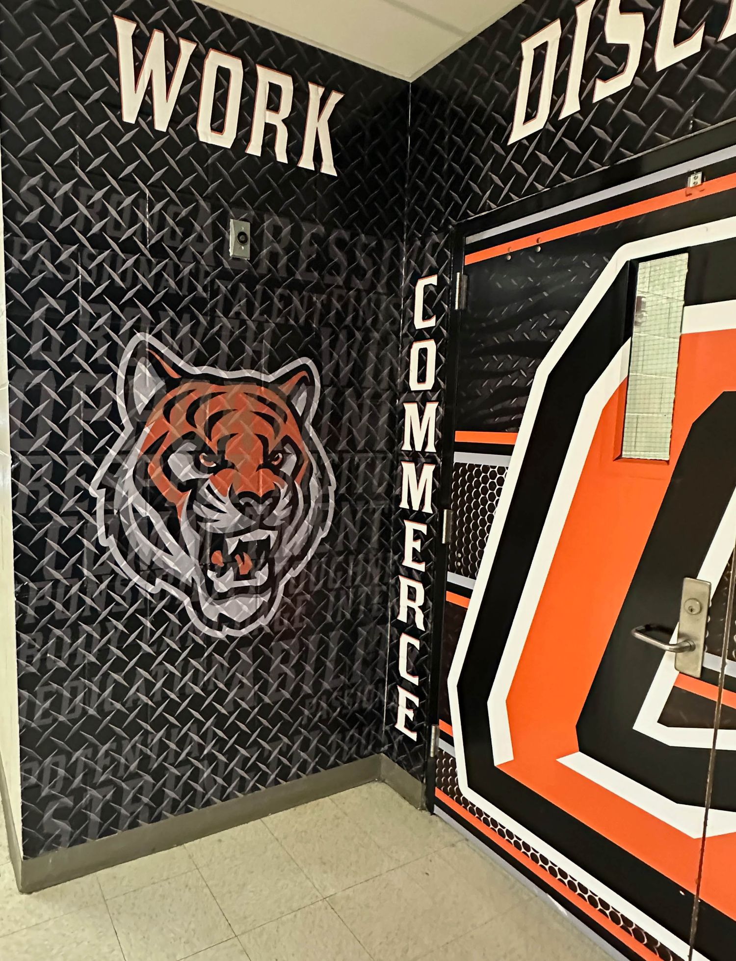Commercial interior wall with a fierce tiger mascot logo and text graphics on black diamond plate background.