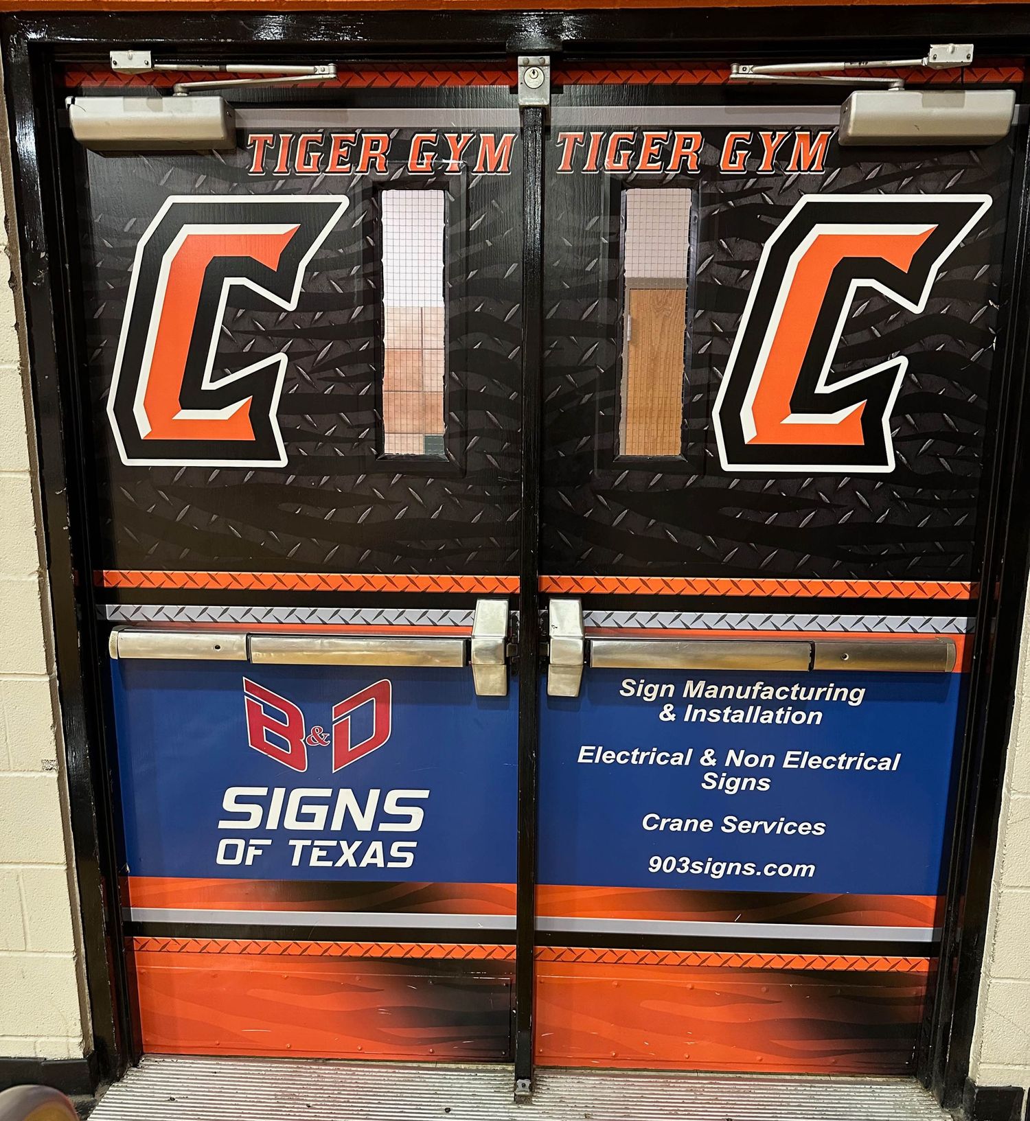Two black doors with Tiger Gym and orange 'C' logos displayed alongside Signs of Texas branding and contact information.