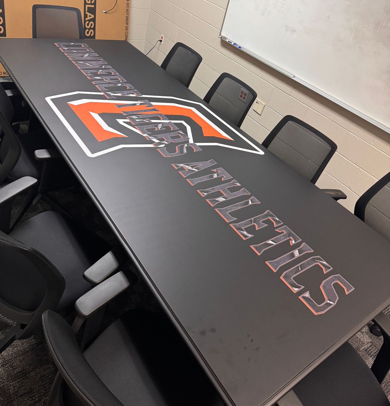 A long conference table with black chairs featuring the Oklahoma State Athletics logo emblazoned on the tabletop.