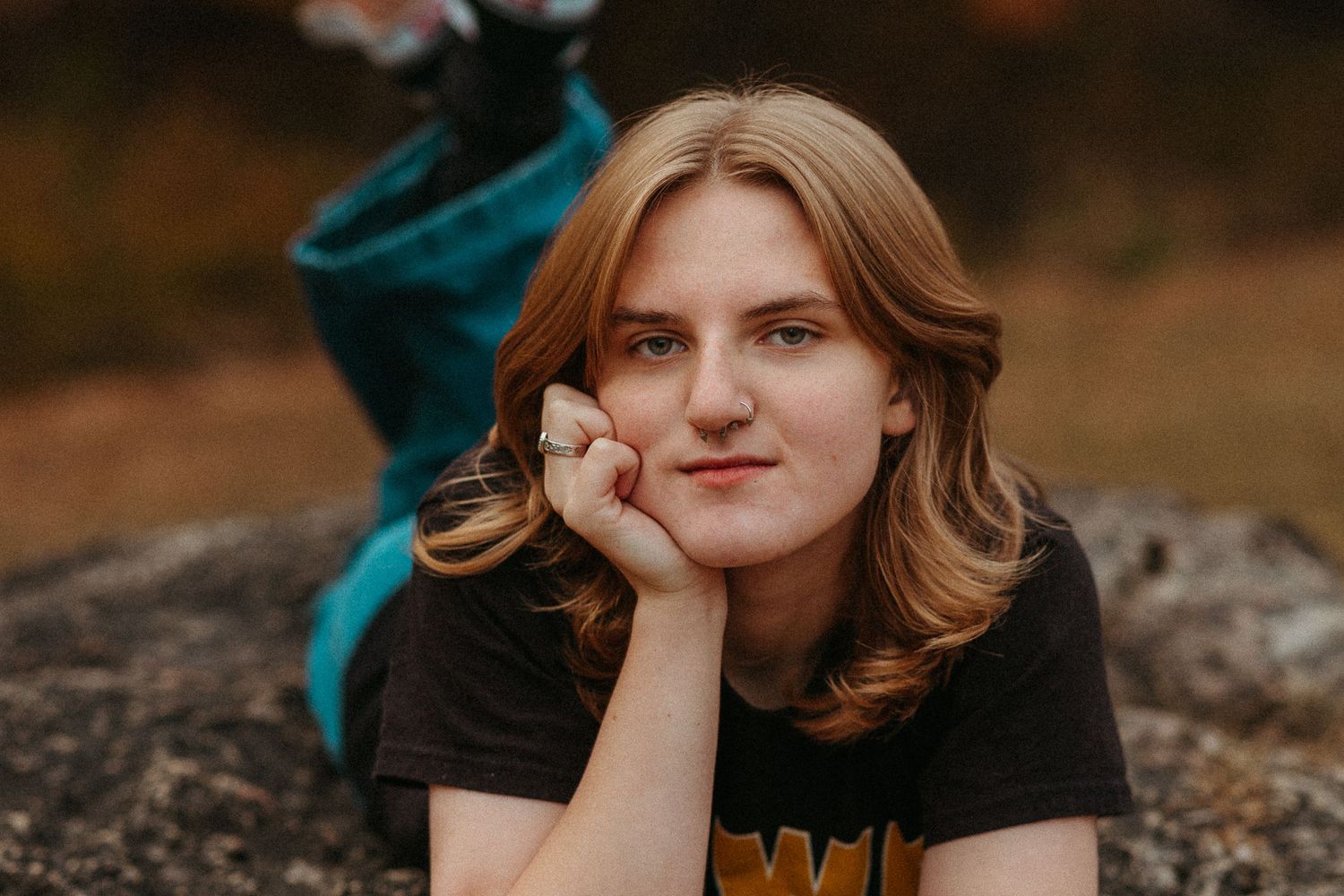 A person in a black t-shirt poses outdoors with a gentle expression.