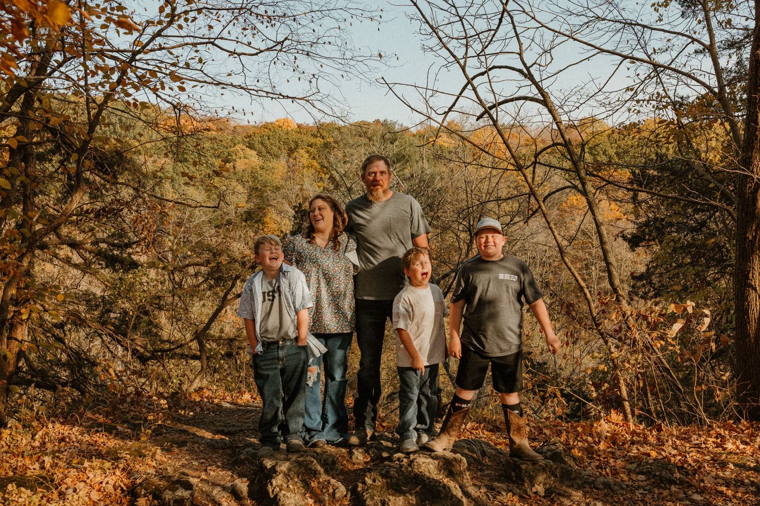Family portrait captured on a rocky trail with autumn foliage in the background.