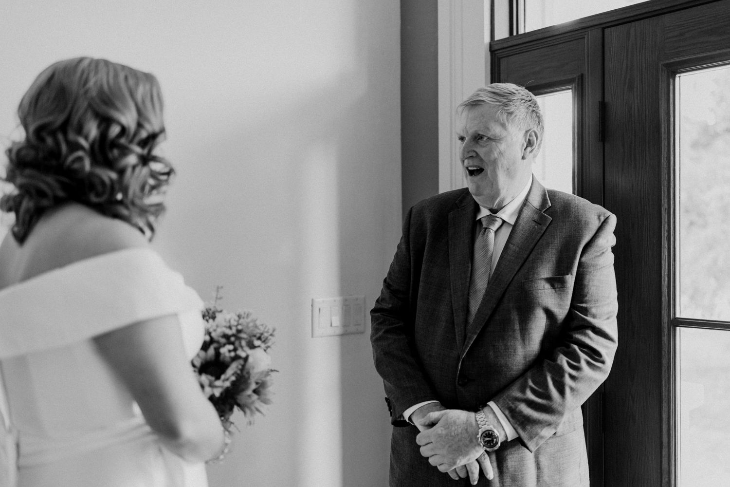 Black and white candid moment between two people during emotional wedding first look.