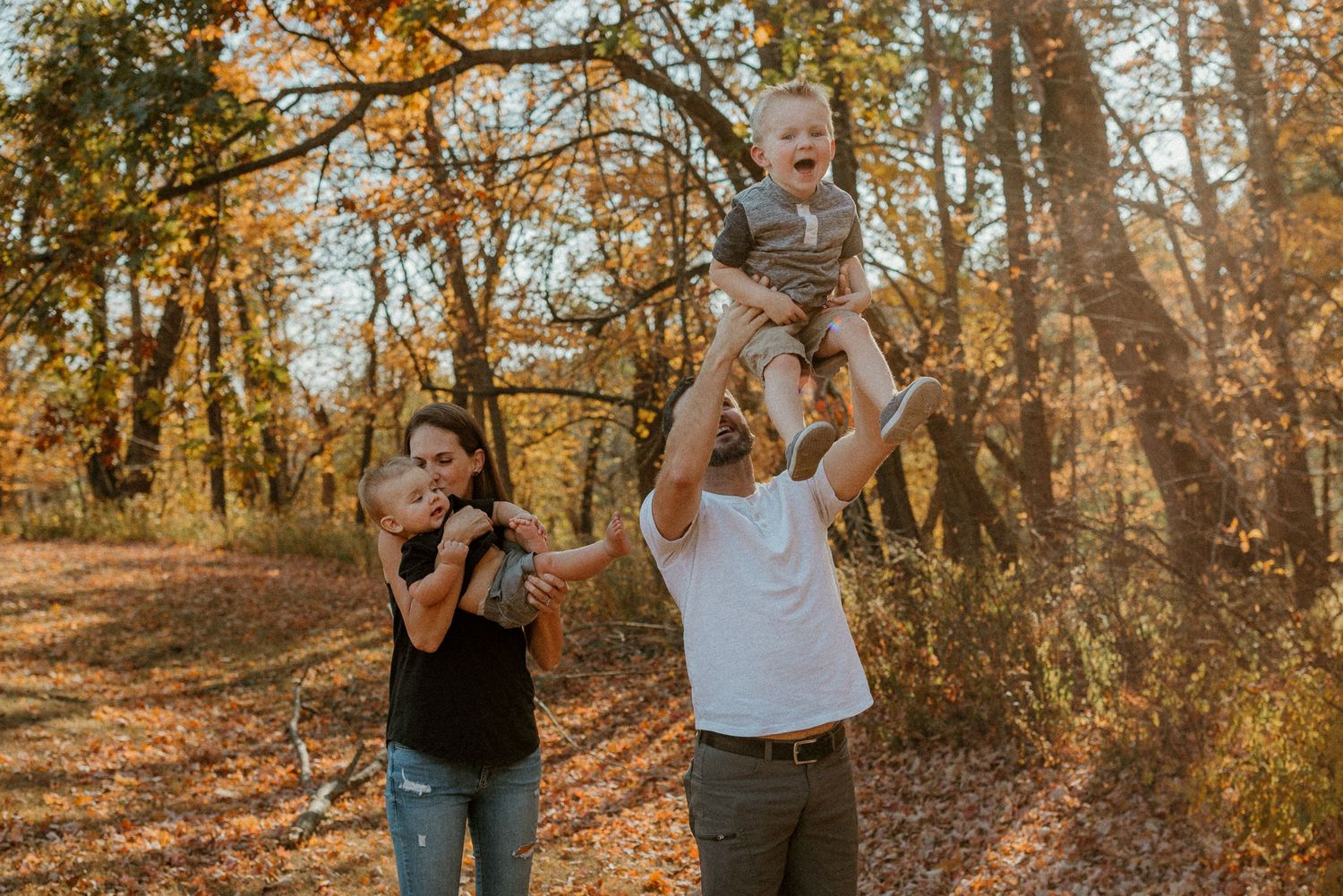 A joyful family moment captured in a golden forest setting during fall.
