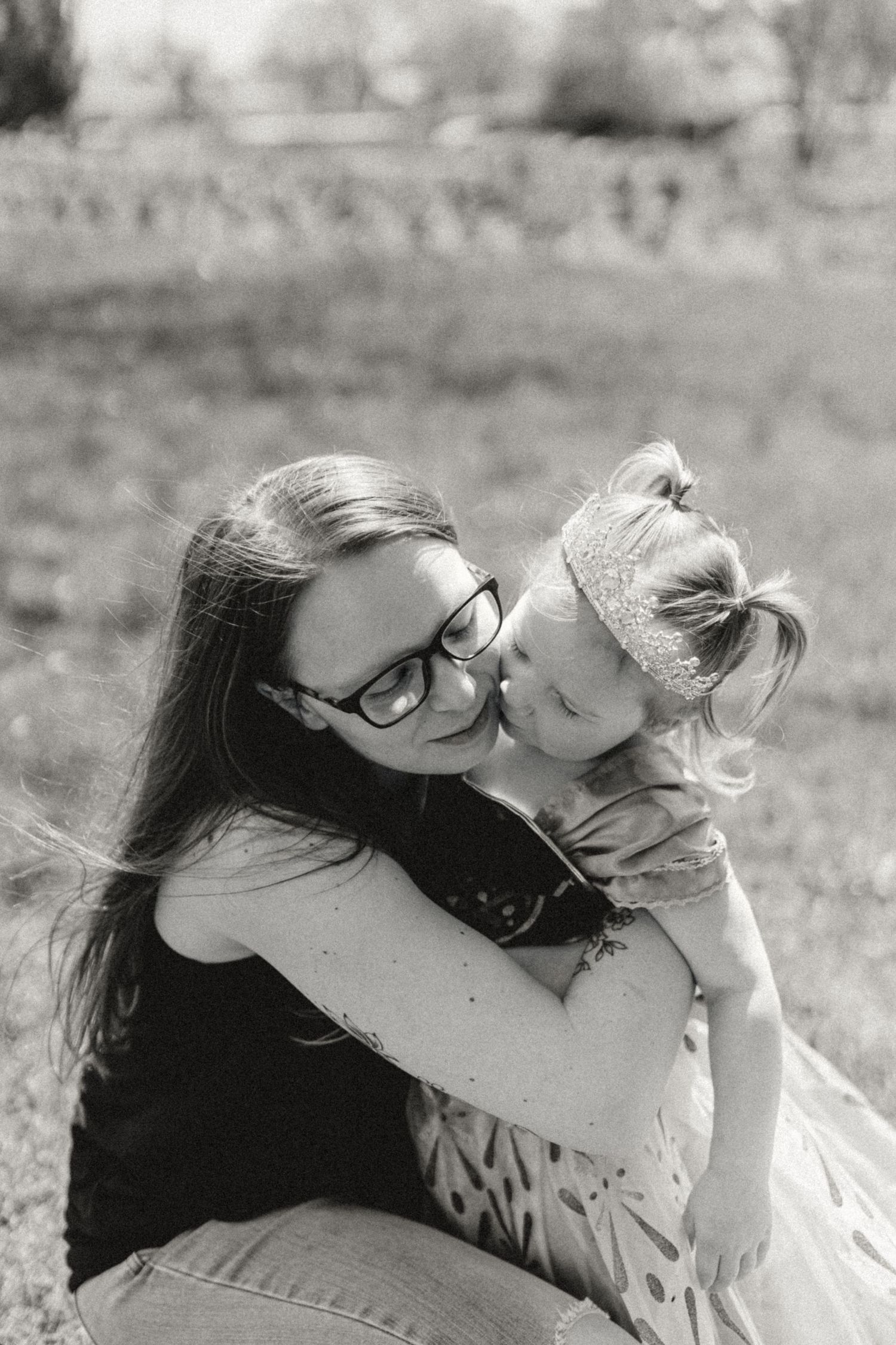 Intimate black and white portrait of a tender moment between siblings outdoors.