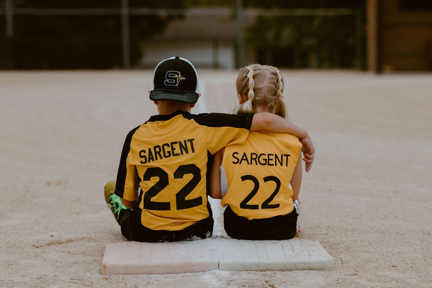 Two sports fans wearing matching yellow Sargent 22 jerseys sitting together on steps.