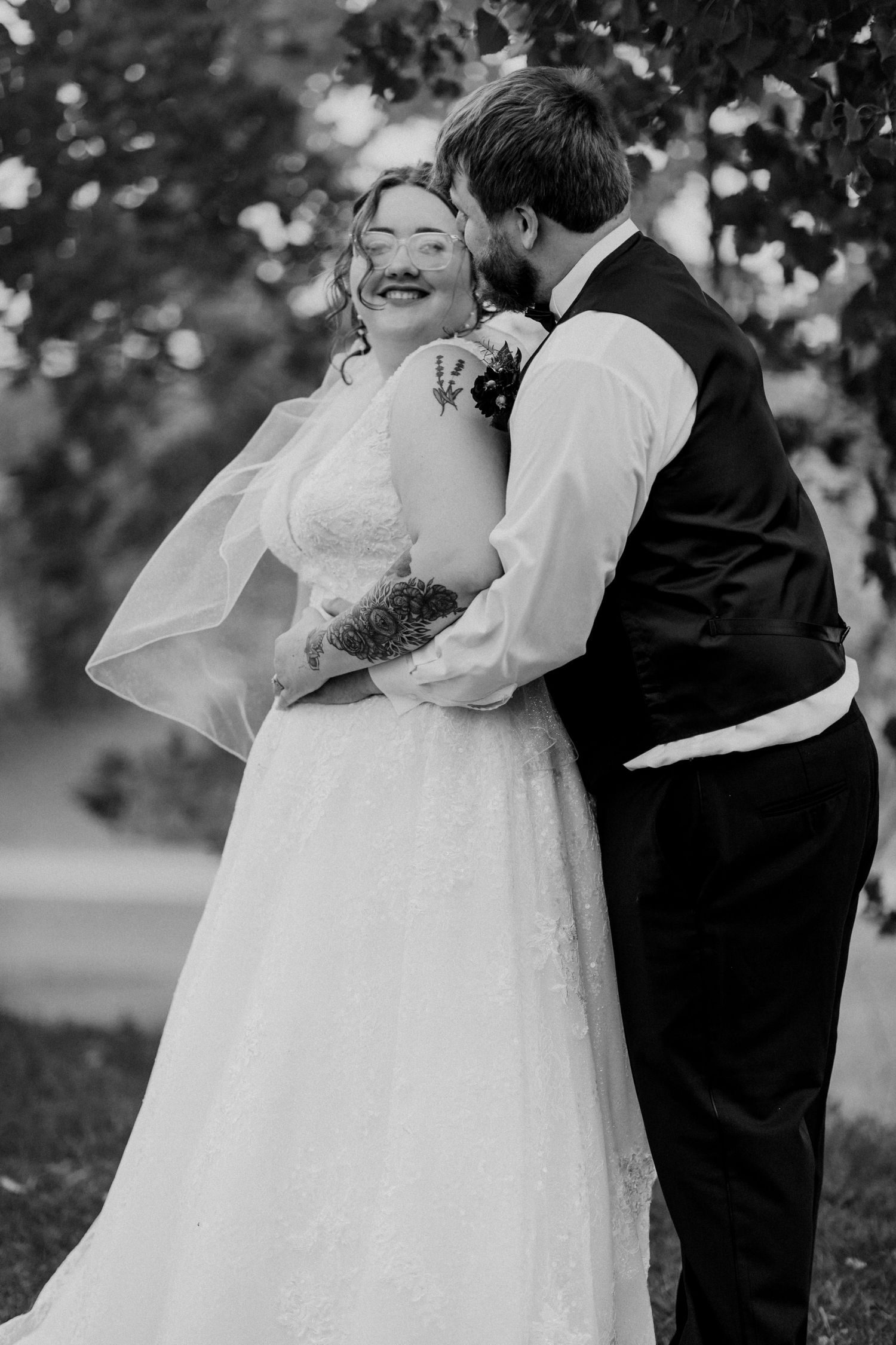 A joyful wedding moment captured in black and white as newlyweds embrace outdoors.