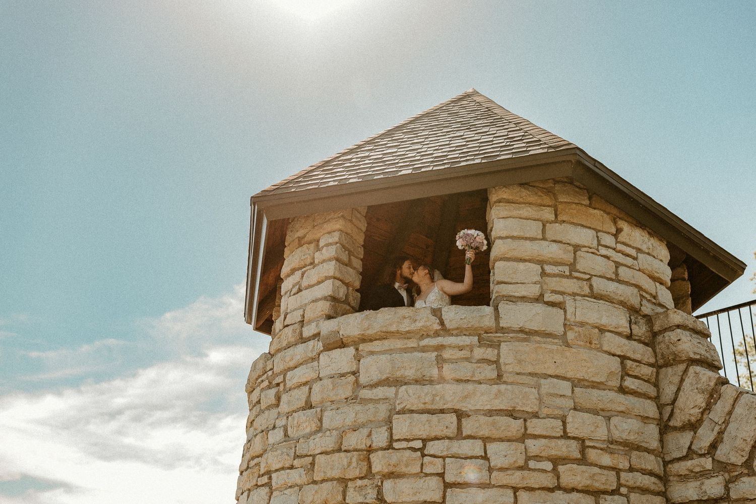 Stone tower window overlooking a bright blue sky and white clouds.