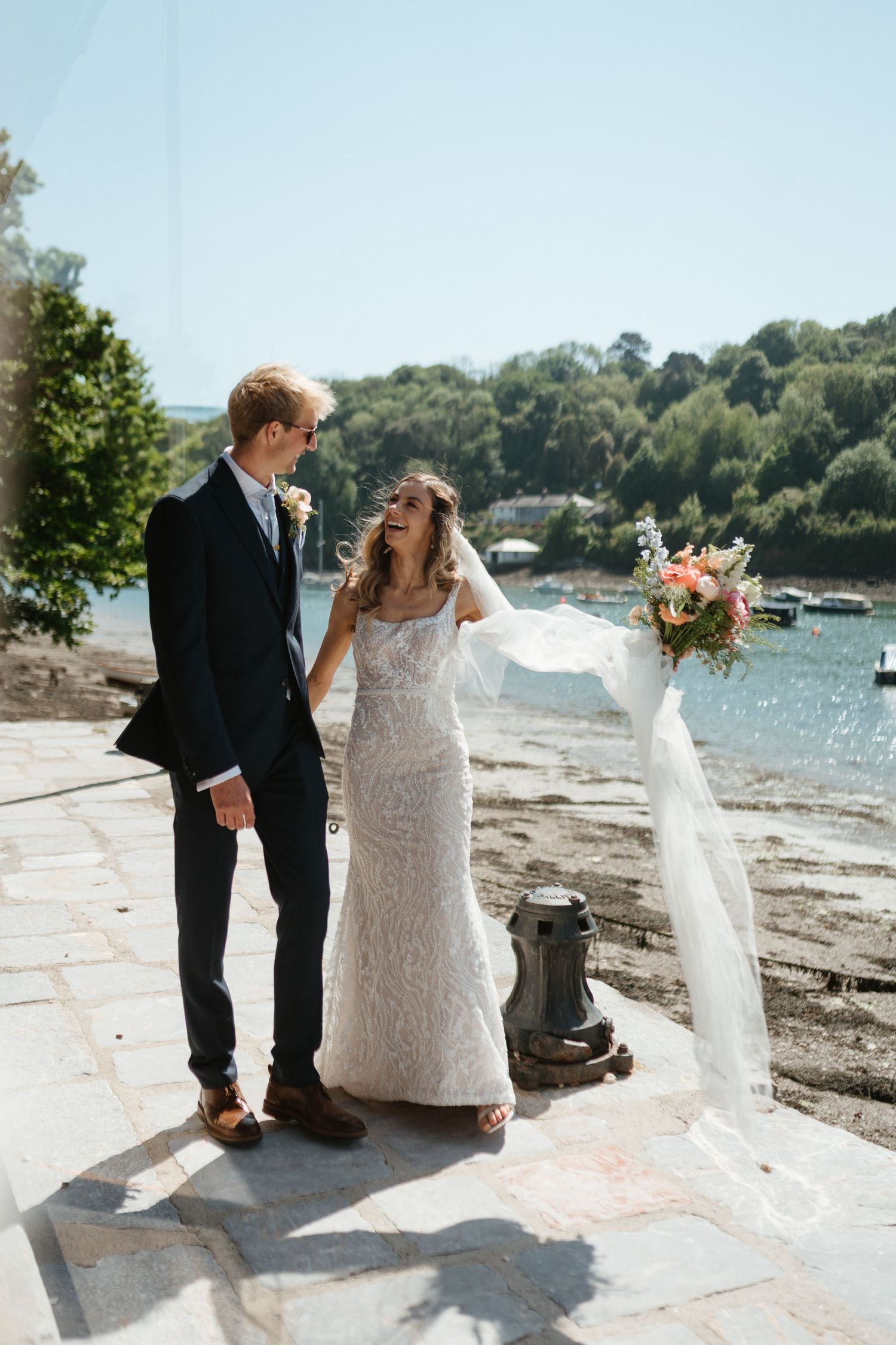 A couple enjoying a tender moment together by the waterfront on their wedding day.