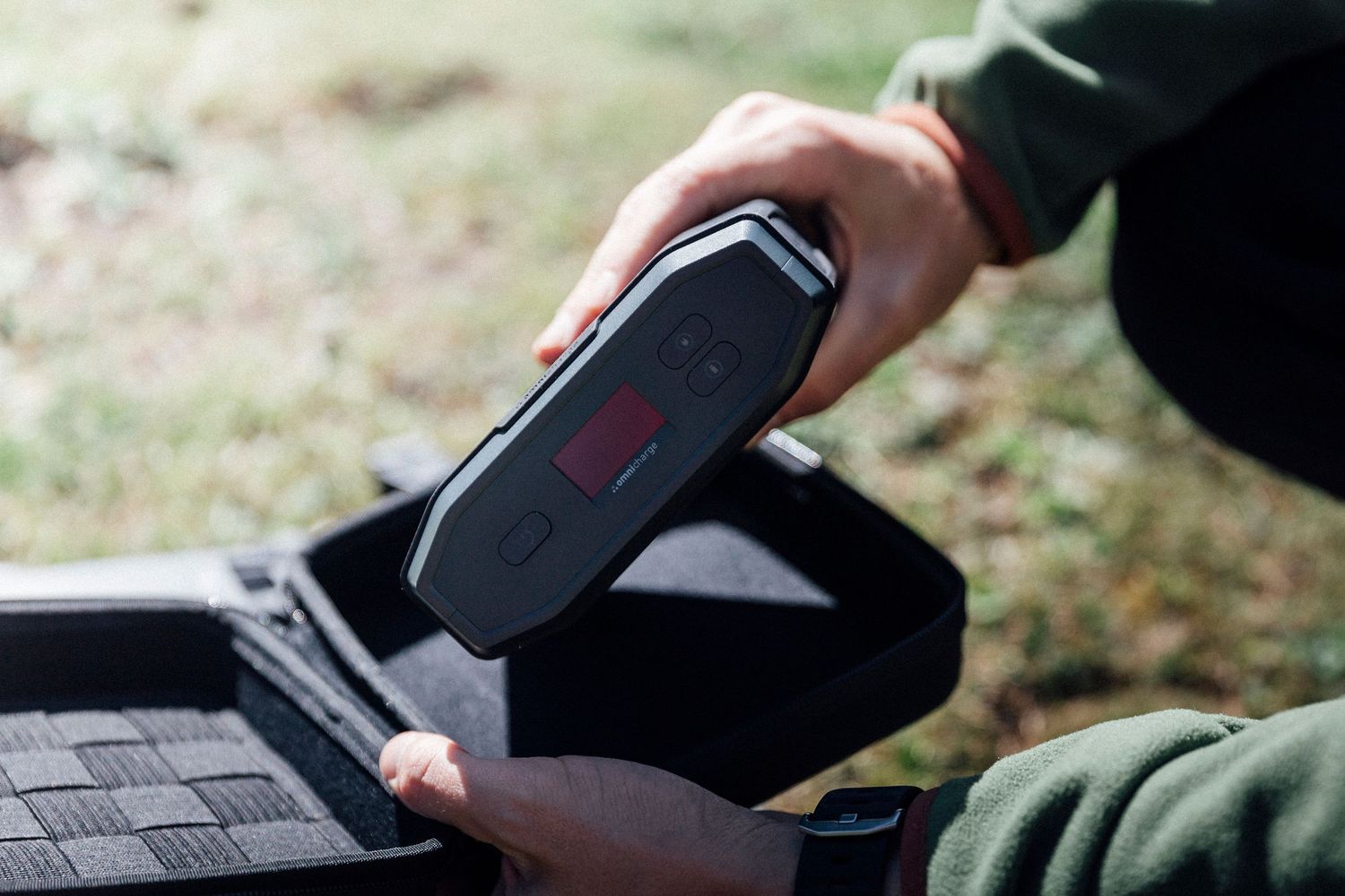 Hand swipes credit card through portable black payment terminal or POS machine outdoors.