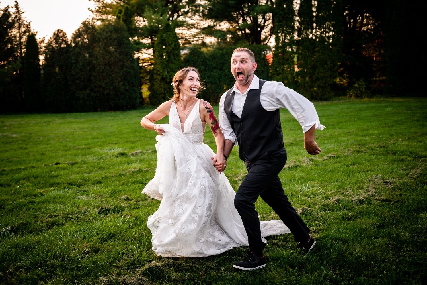 Newlyweds dance and celebrate on a lush green lawn during their outdoor wedding reception.
