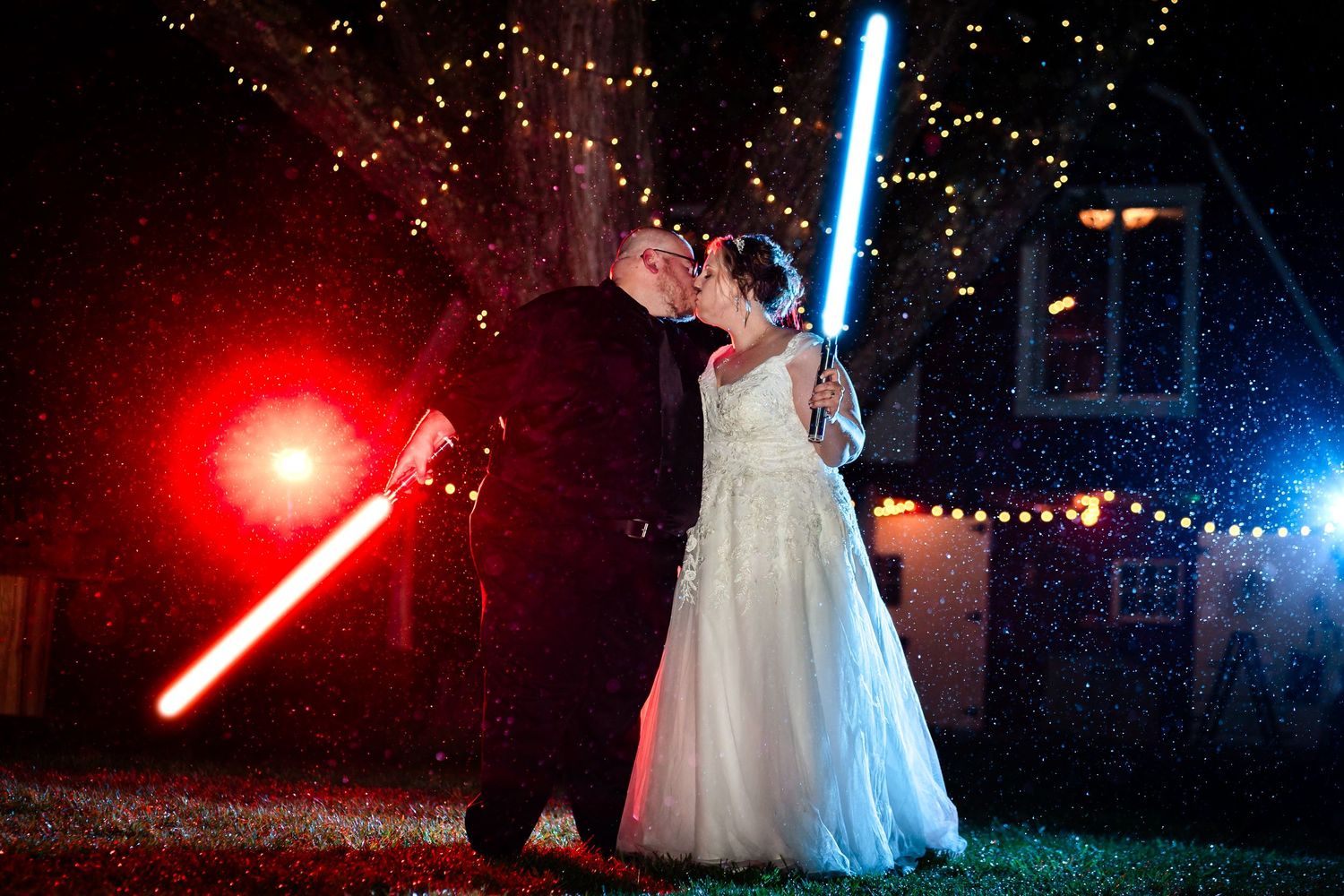 Wedding couple with lightsabers creating colorful light effects at night.