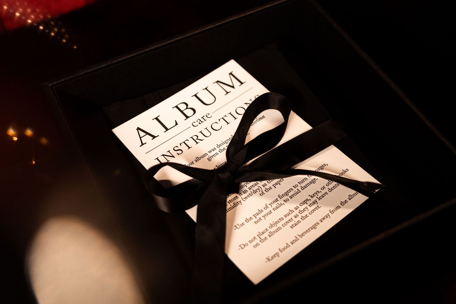 Wedding stationery and album details captured in dramatic low-key lighting.