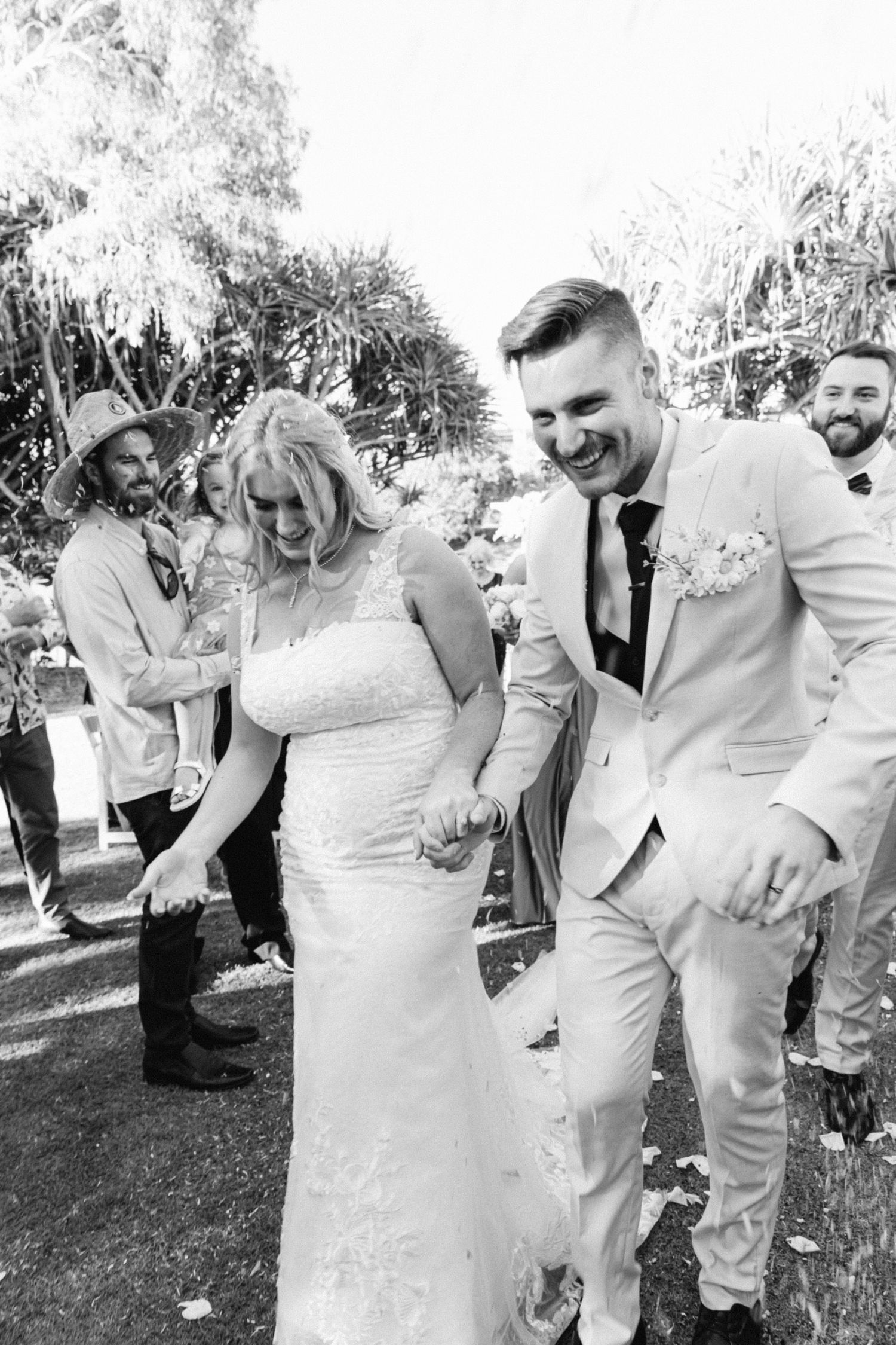 Black and white candid photos of wedding party laughing together outdoors.