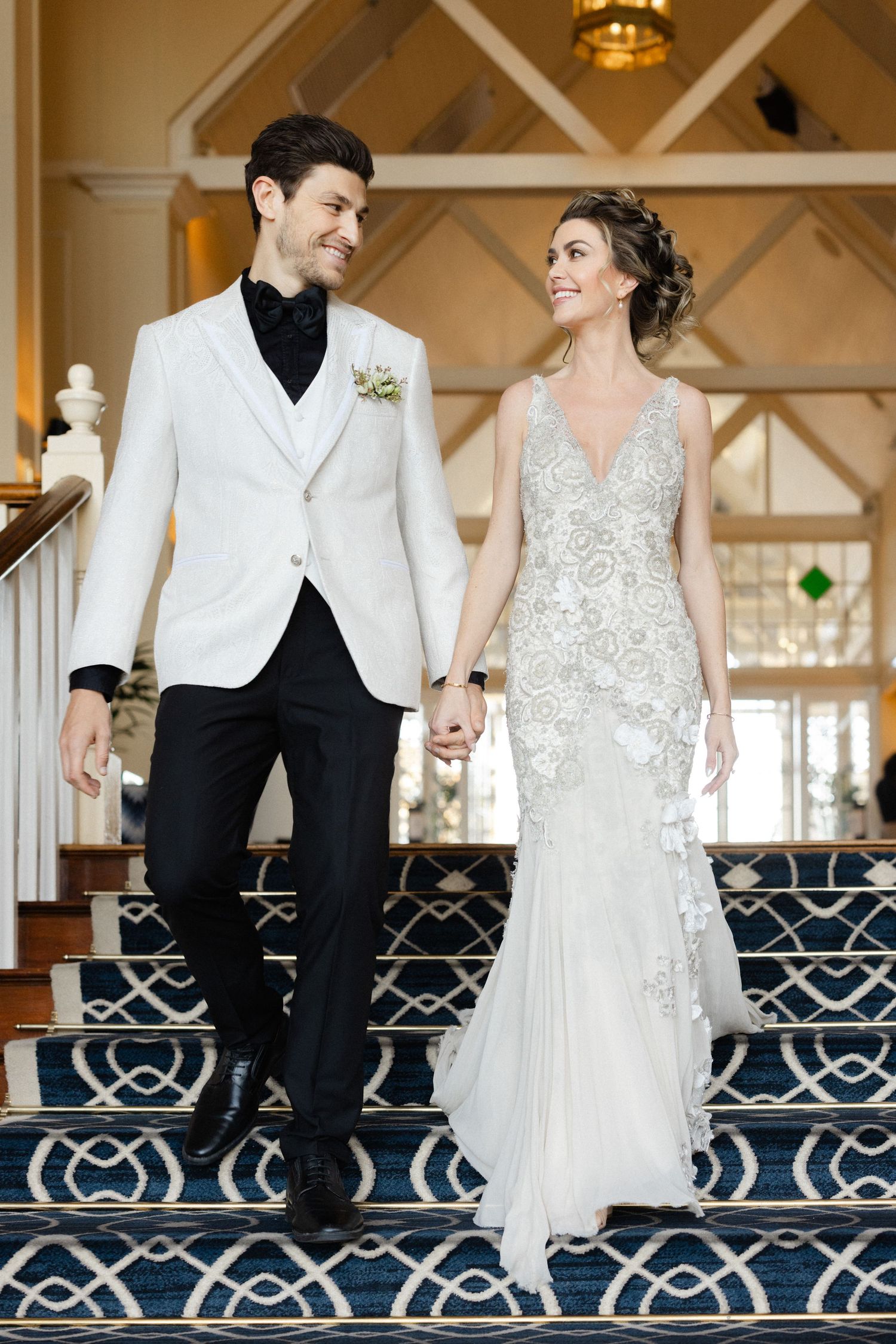 A bride and groom share a romantic dance moment on an ornate blue carpet in a wedding venue.