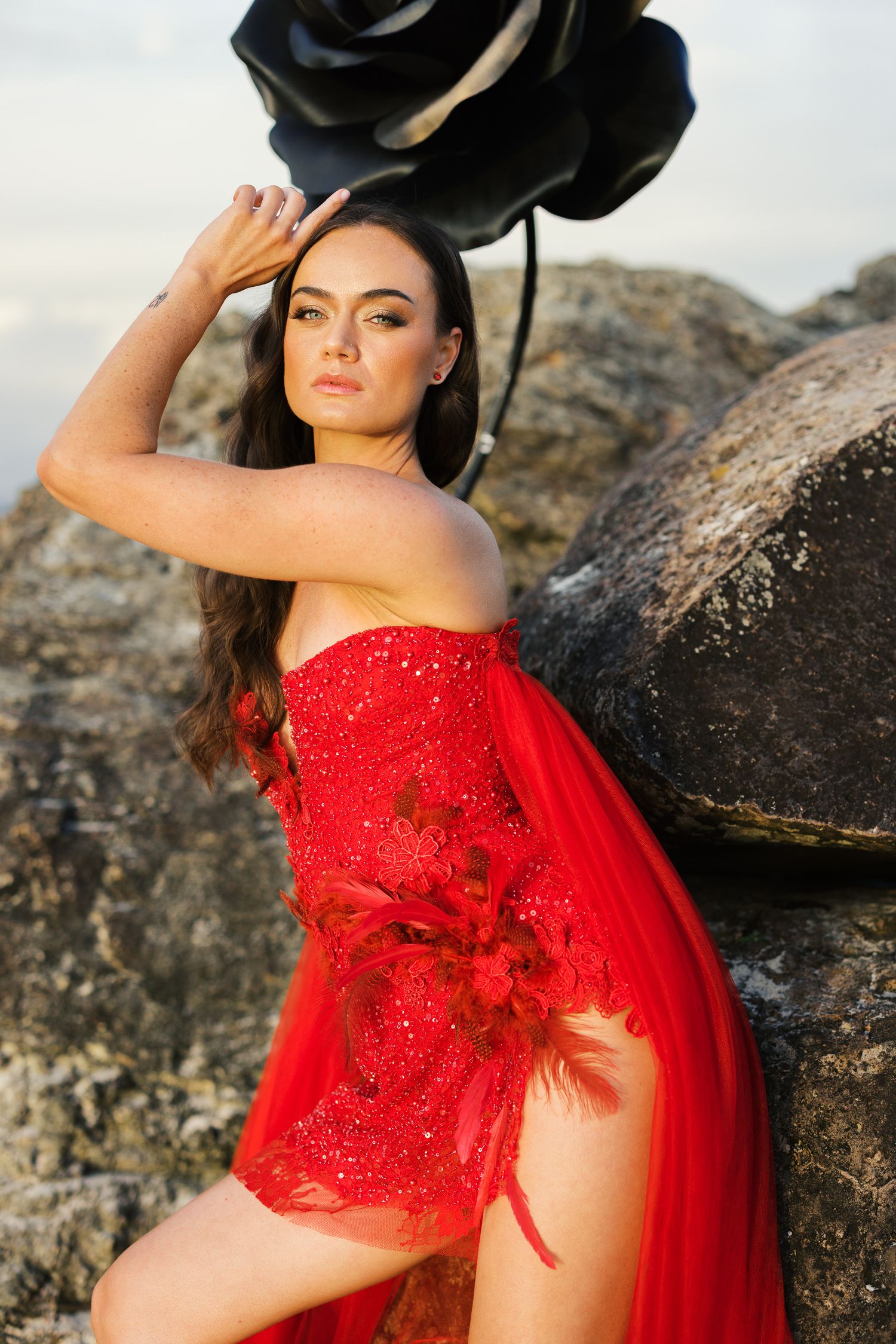 Glamorous red sequined dress with flowing fabric captured in dramatic outdoor portrait session.