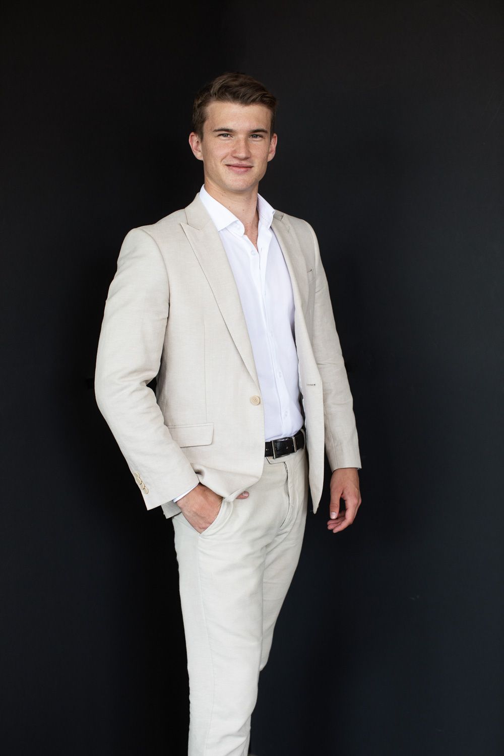 A series of professional studio portraits showing a person in a crisp white suit against a dark background.