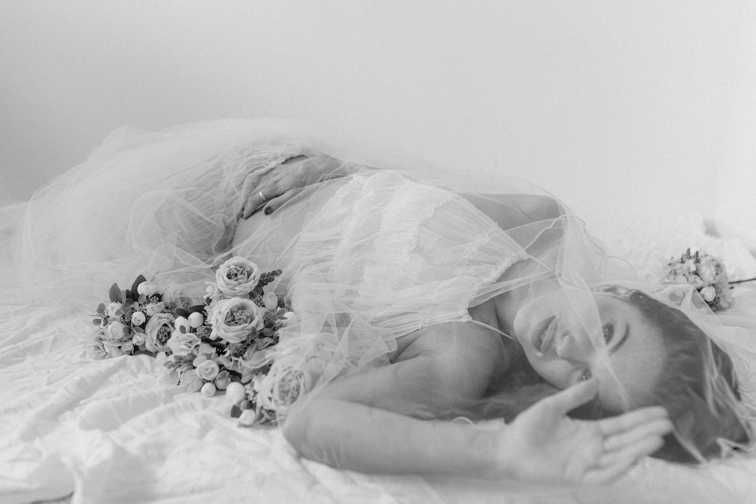 A dreamy black and white photograph showing delicate lace and floral arrangements in a soft, ethereal composition.