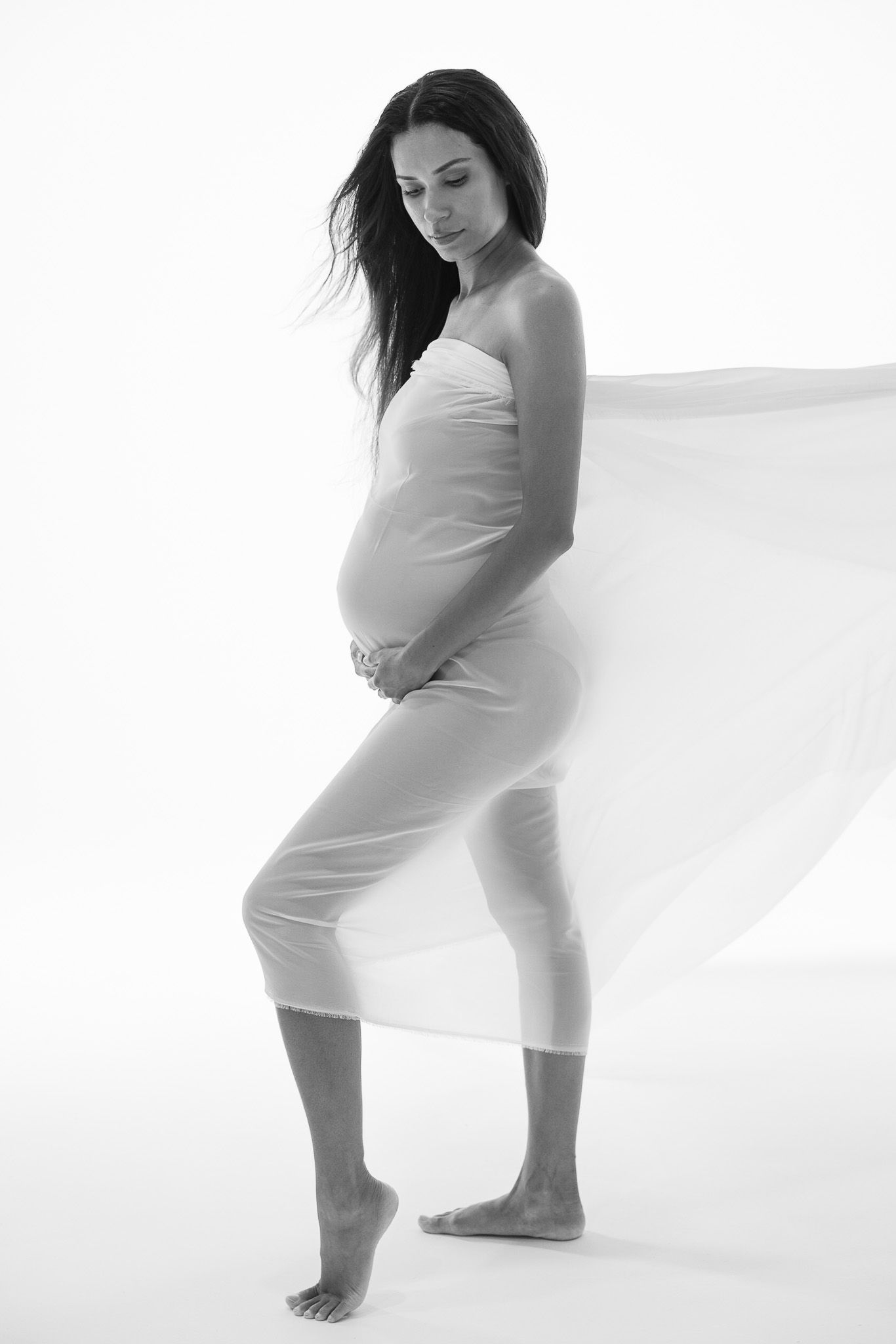 A figure in a white dress poses gracefully against a minimalist backdrop in a series of artistic movements.