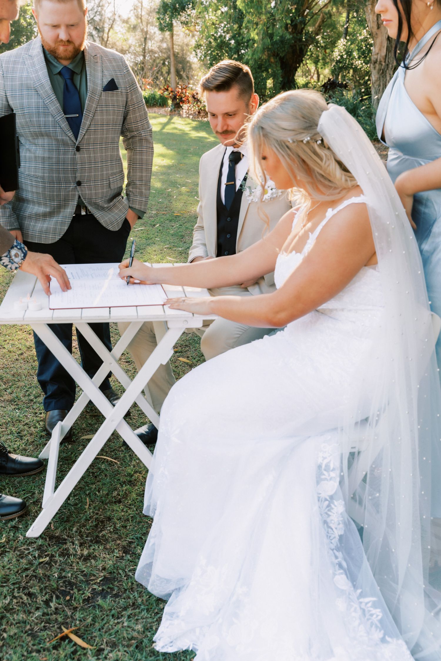 Wedding ceremony signing photos with couple and witnesses at outdoor venue.
