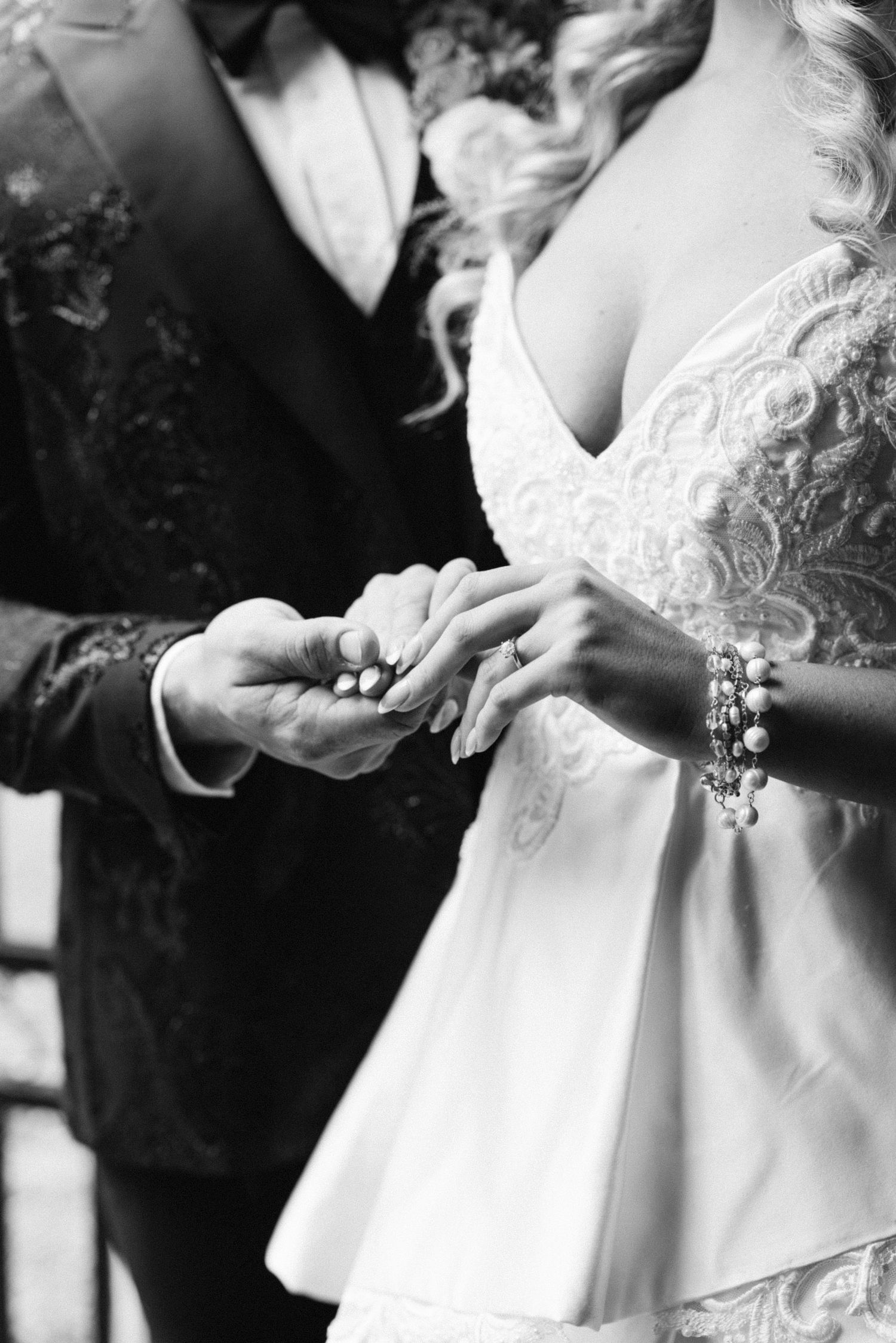 Black and white detail shots of hands adjusting wedding dress.
