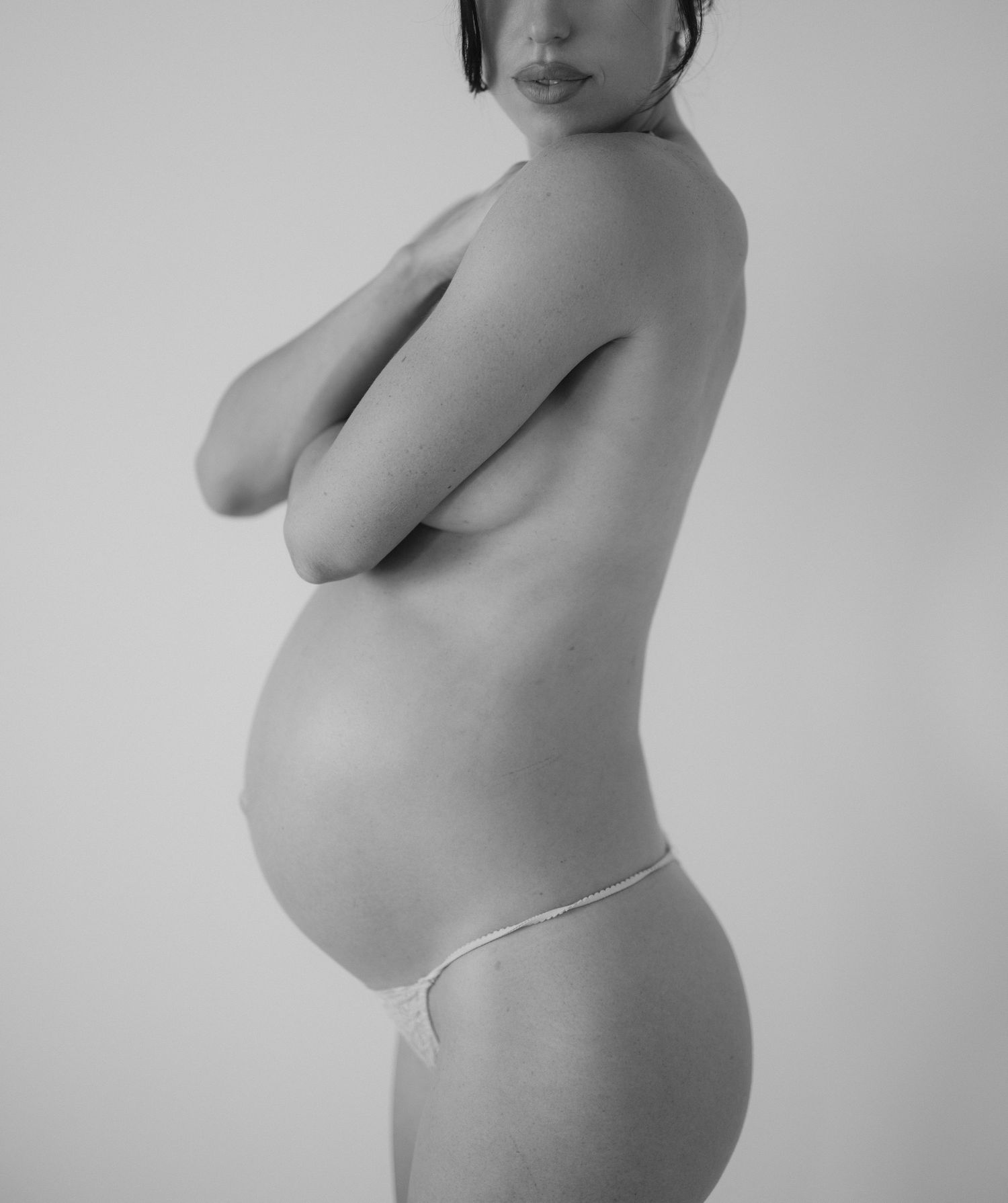 Black and white artistic maternity photo showing a pregnant woman's silhouette in profile against a light background.