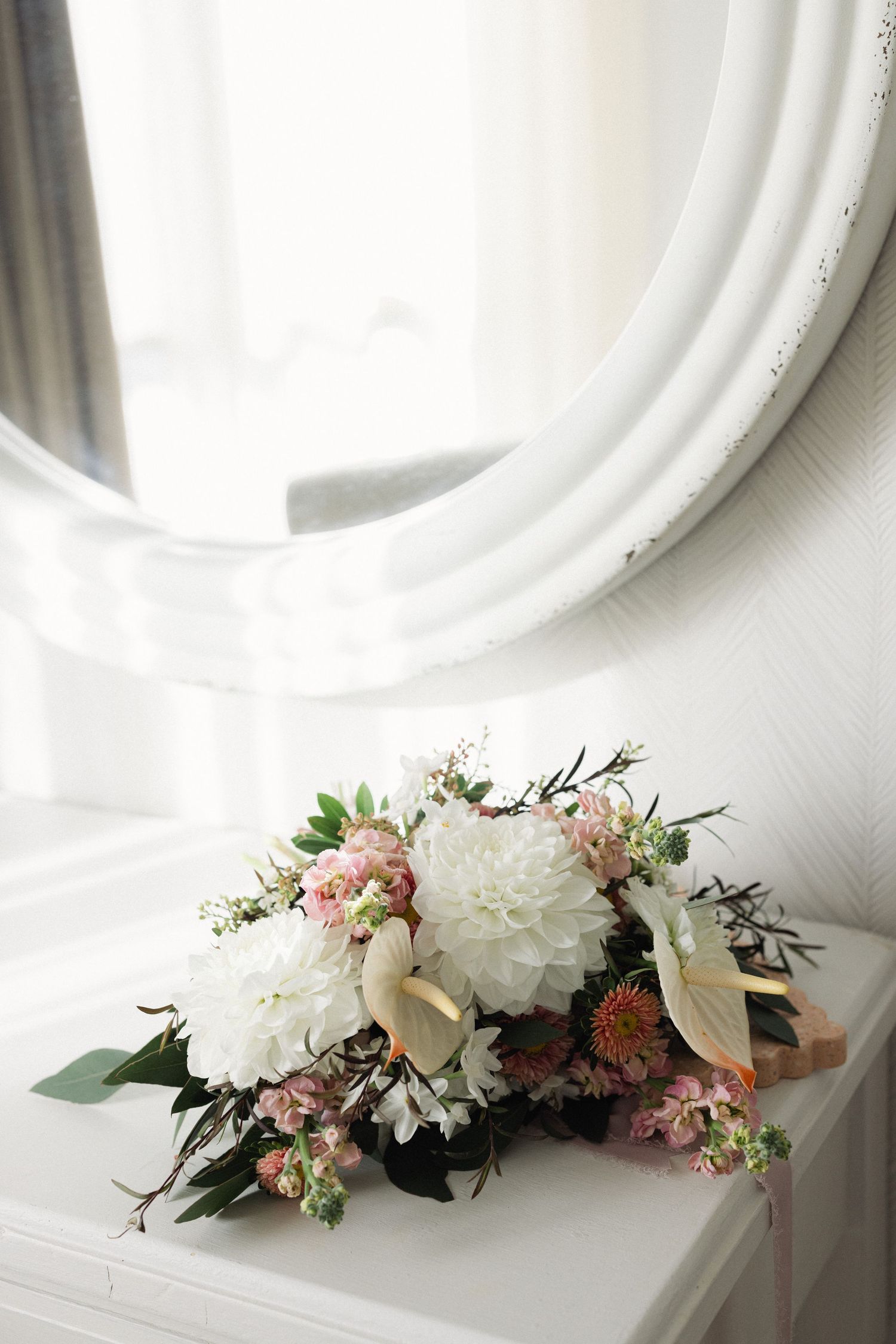 A series of elegant white and pink floral arrangements displayed on a white surface against a white wall.