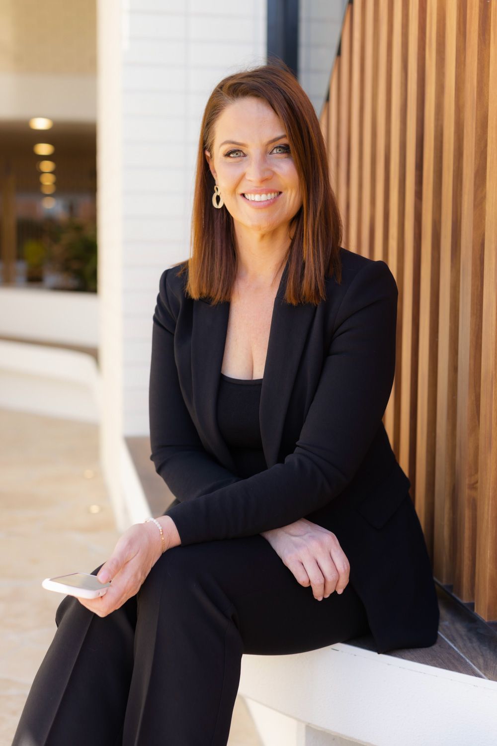 Professional headshots series against wooden panel background in business attire.