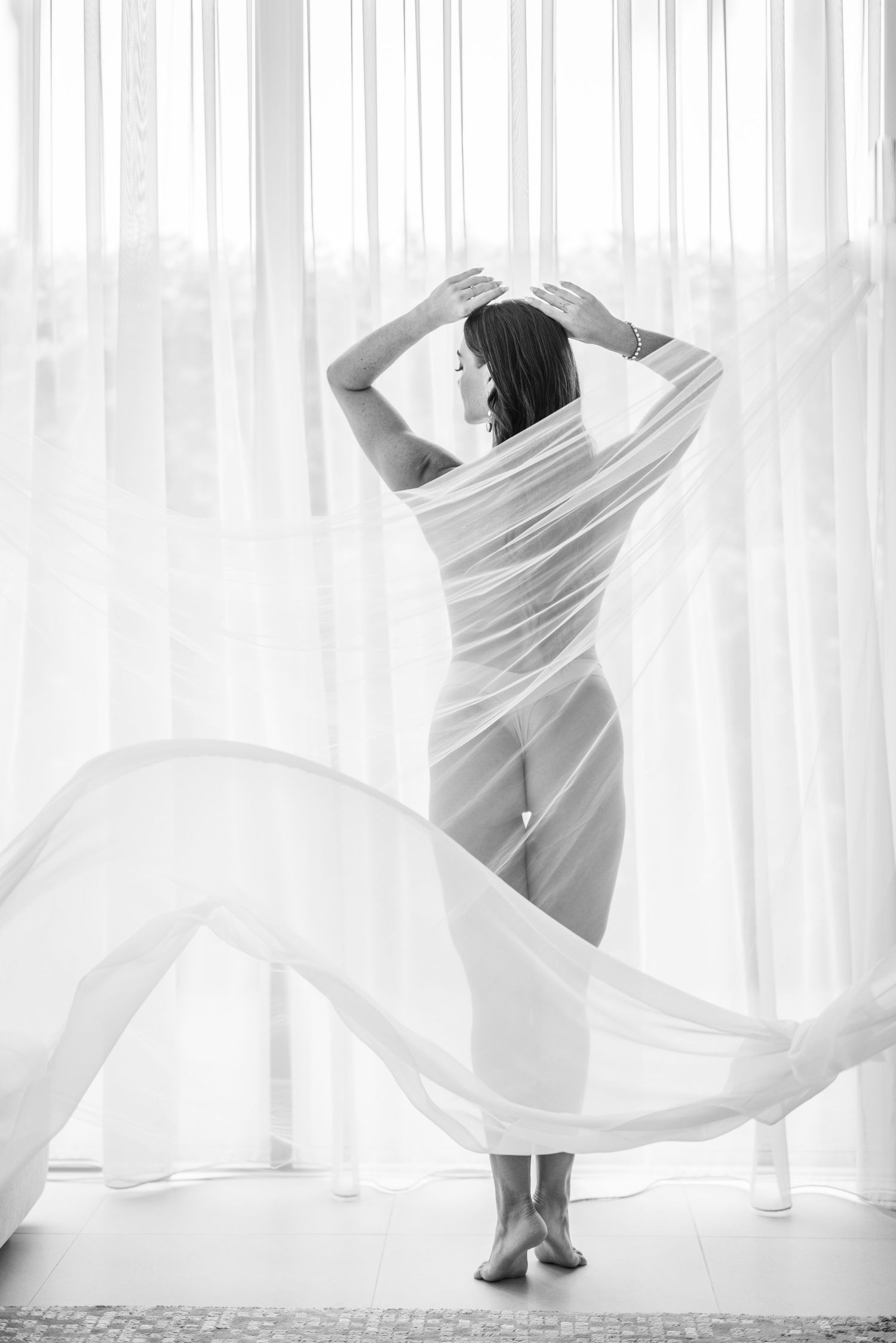 Artistic sequence of flowing white fabric movement against bright window light.