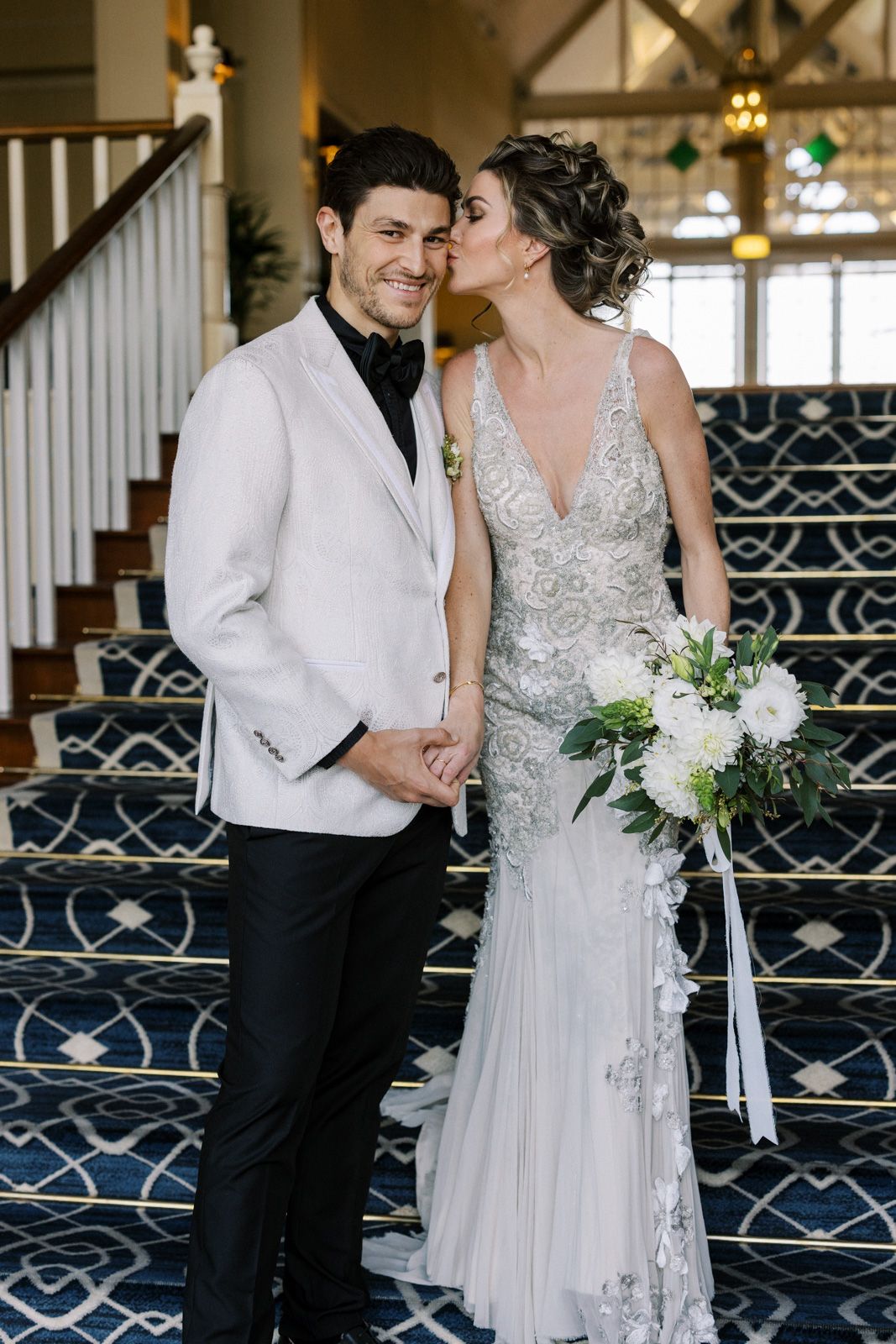 A romantic wedding couple sharing an intimate moment on a staircase with navy patterned carpet.