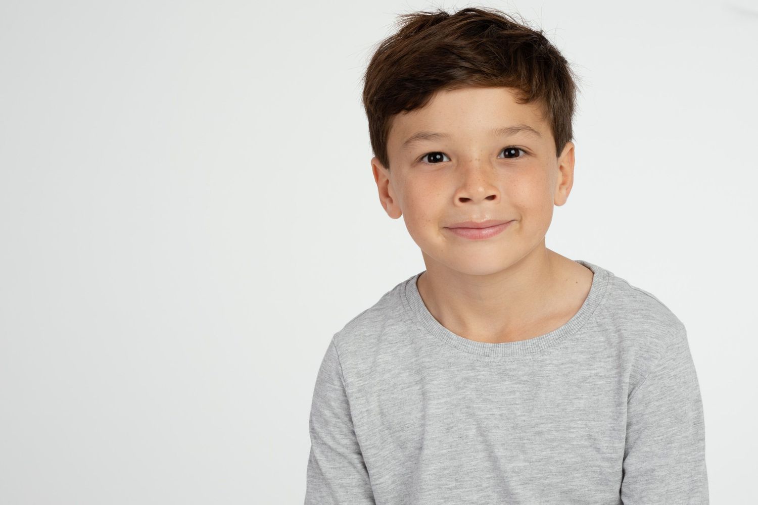 Young child wearing gray shirt against white background.