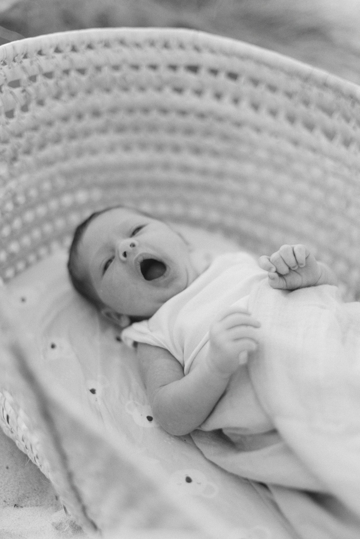 A black and white image shows a sleeping baby in white clothing against a textured background.