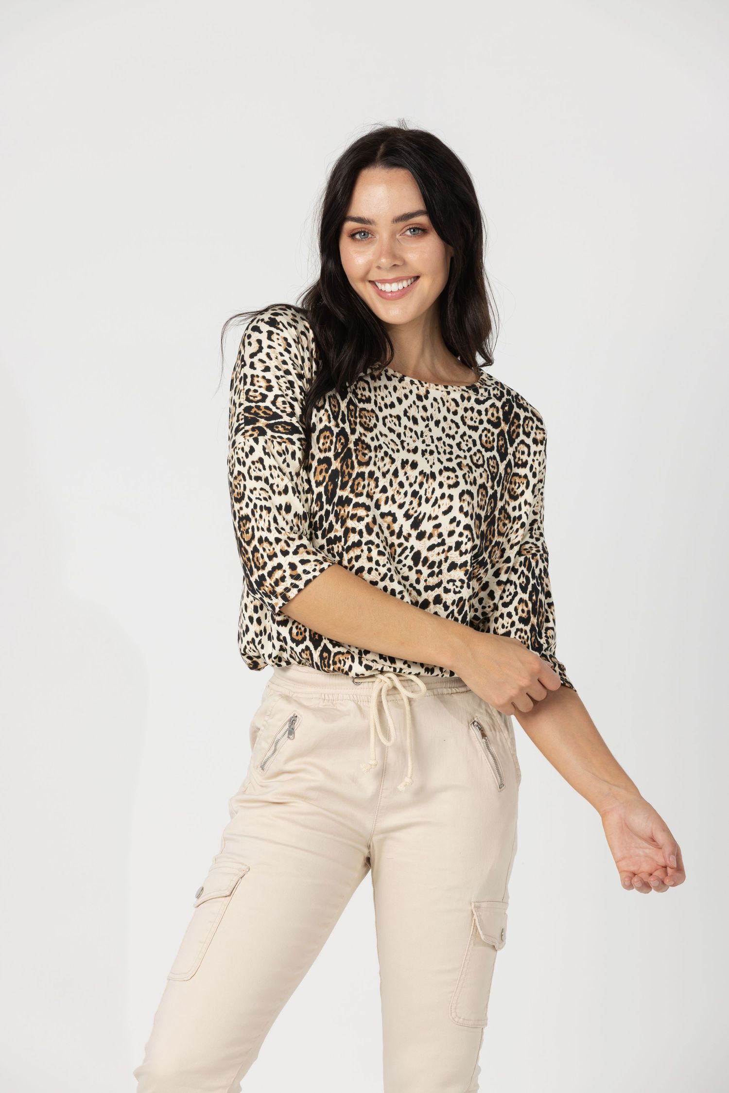 Woman wearing a stylish leopard print top and cream colored cargo pants in a fashion photoshoot.