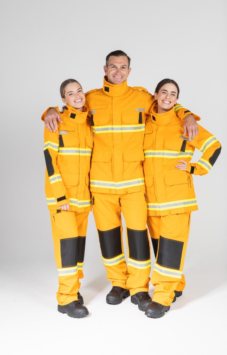 Three people wearing bright yellow safety uniforms with reflective stripes posing together.