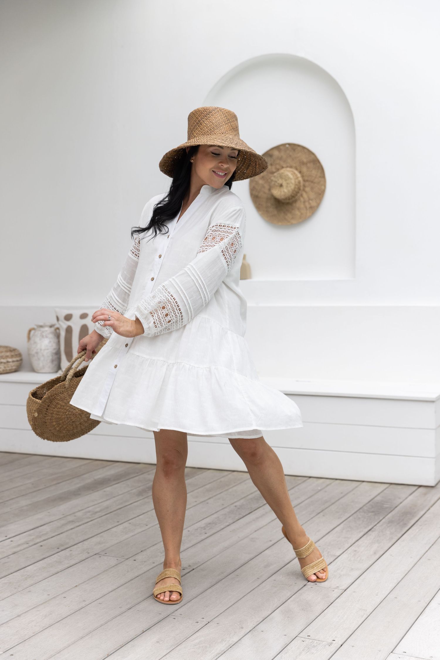 White summer dress with twirling motion shown against light wooden floor and white wall background.
