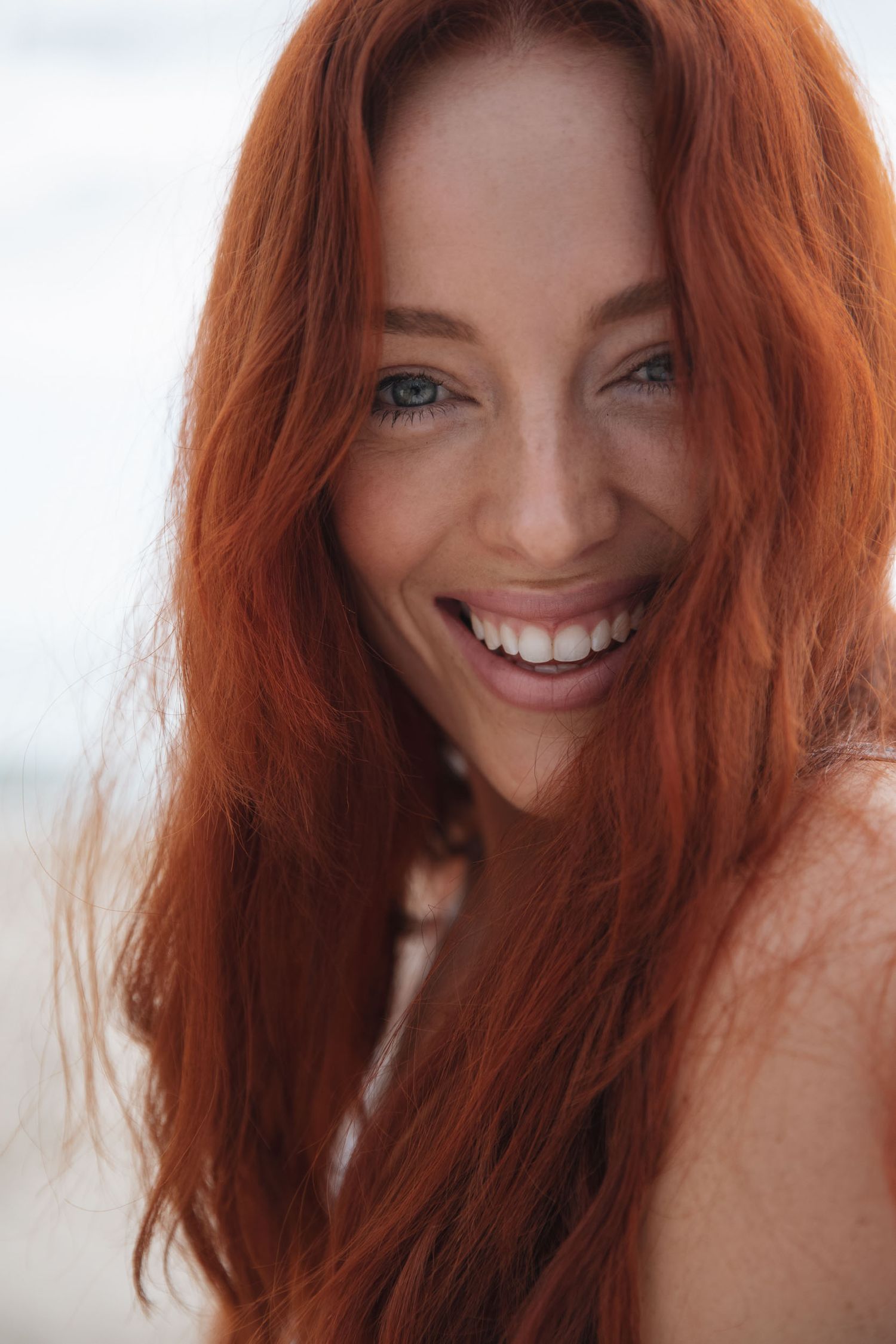 Close up beauty portrait with vibrant red hair and natural smile.