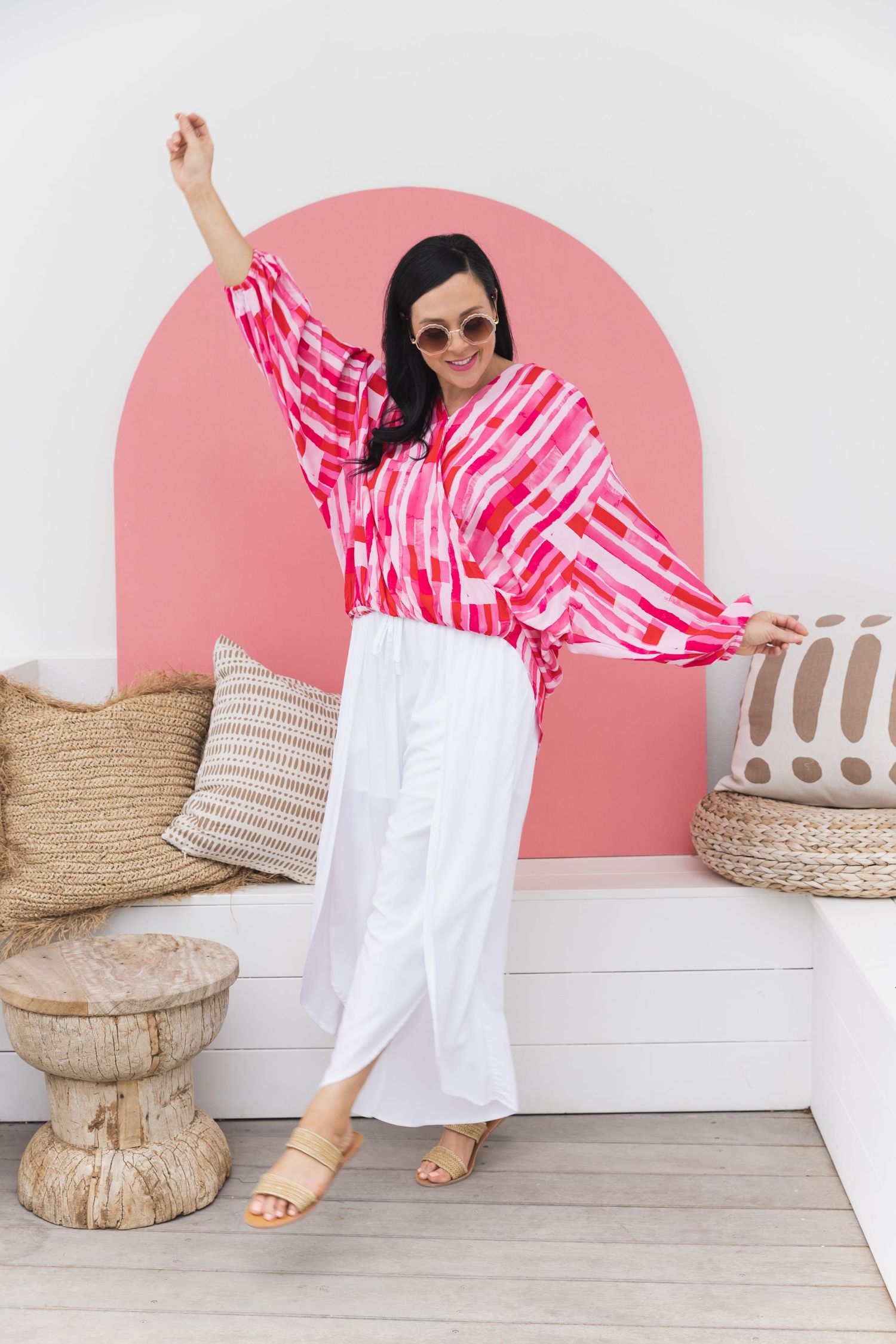 Pink and white tie-dye dress styled with woven baskets against pink curved wall accent.
