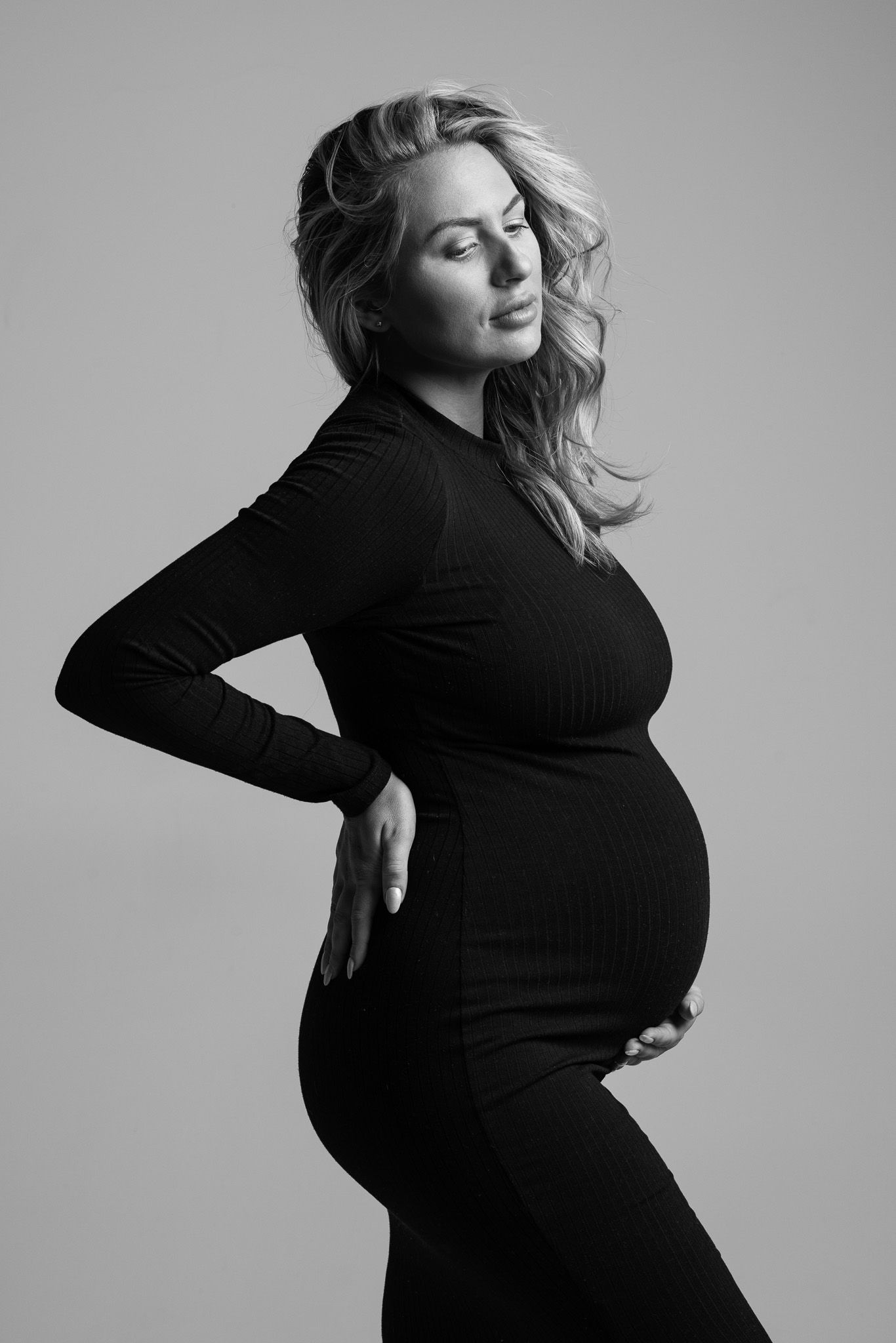 Artistic black and white maternity portraits showing a woman in a black turtleneck against a light background.