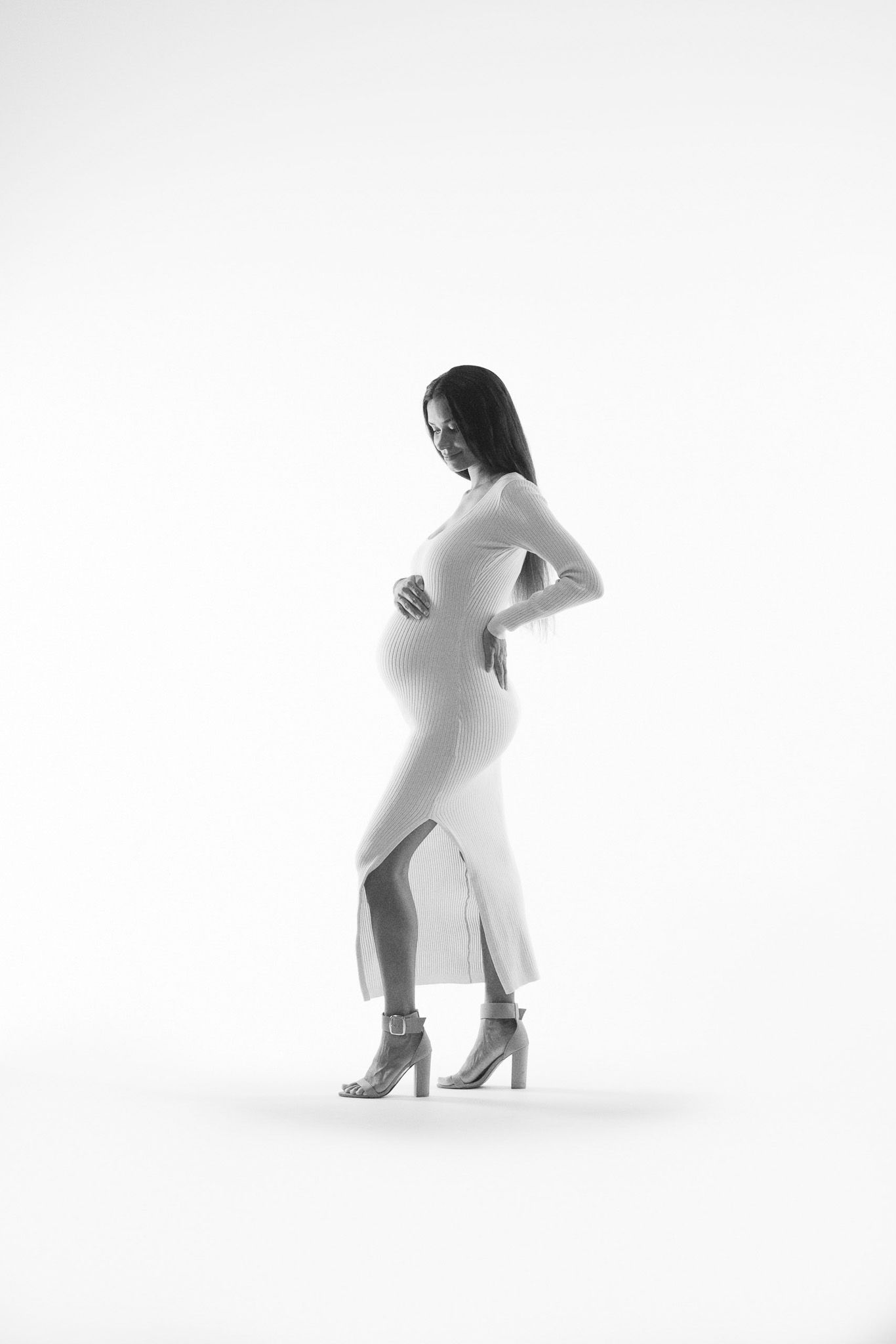 A figure in a white bodysuit performs a dynamic dance movement against a minimalist white background.