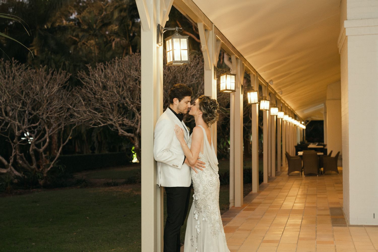 A series of illuminated outdoor walkways with white columns and lanterns creating an elegant architectural perspective.