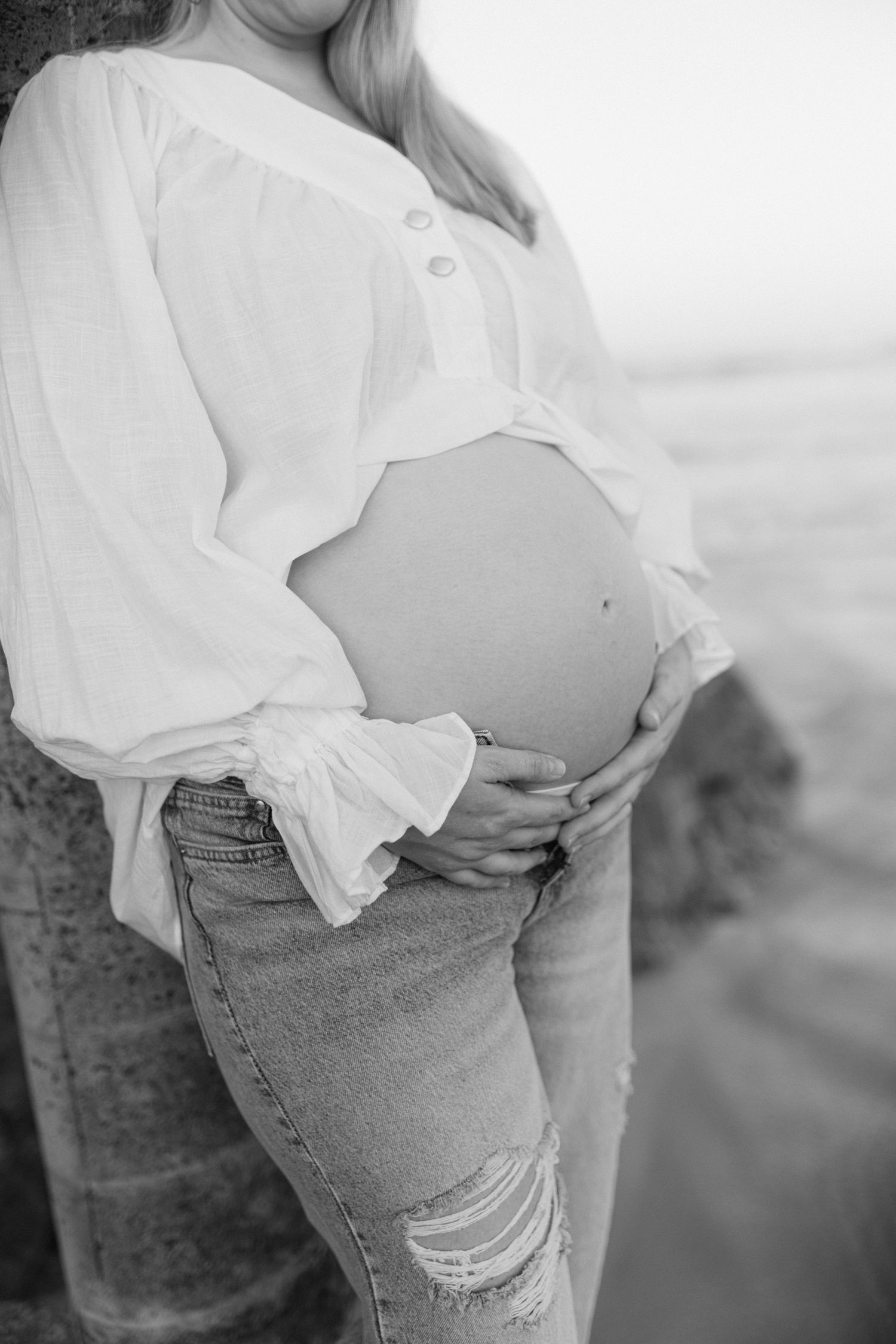Series of maternity photos showing a pregnant belly with white blouse and distressed jeans in natural light.