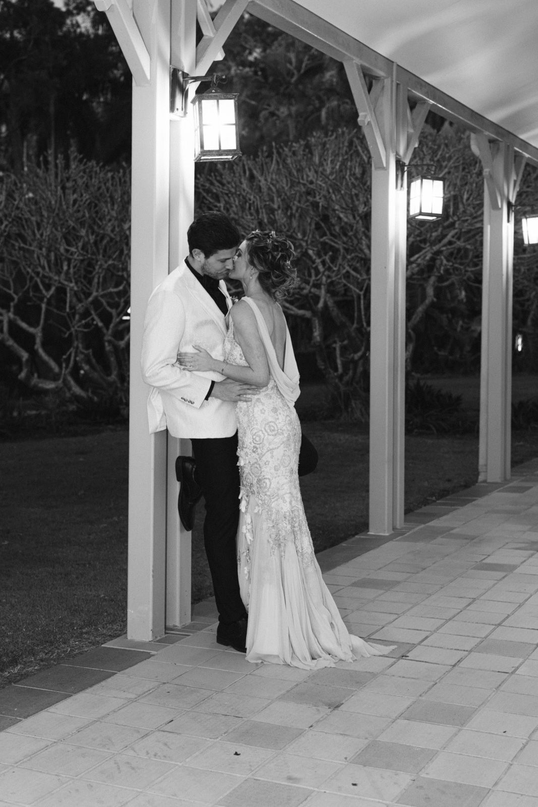 A romantic sequence of black and white photos showing a couple in formal attire sharing intimate moments under a covered walkway.