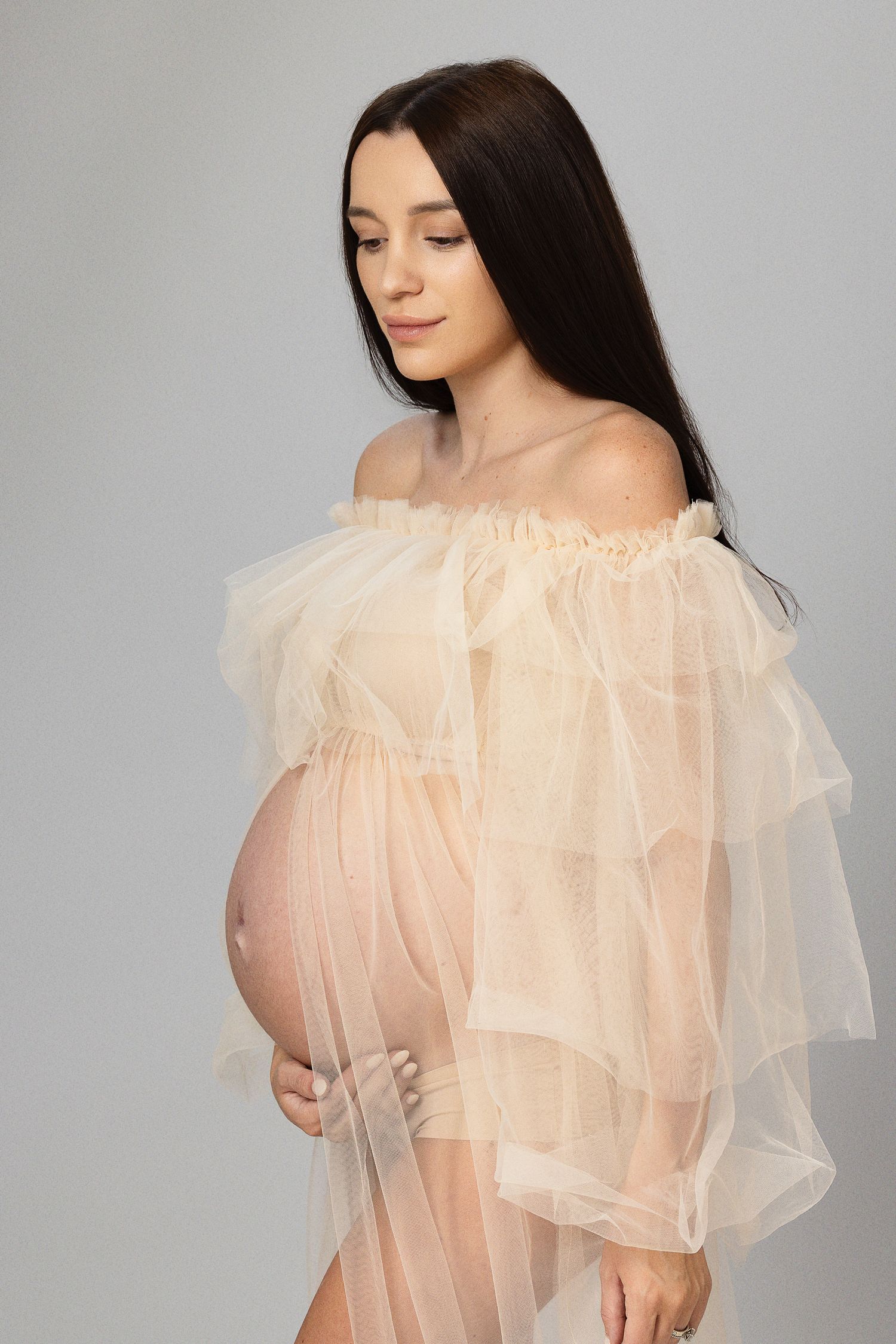 Elegant maternity portrait in sheer peach tulle gown.