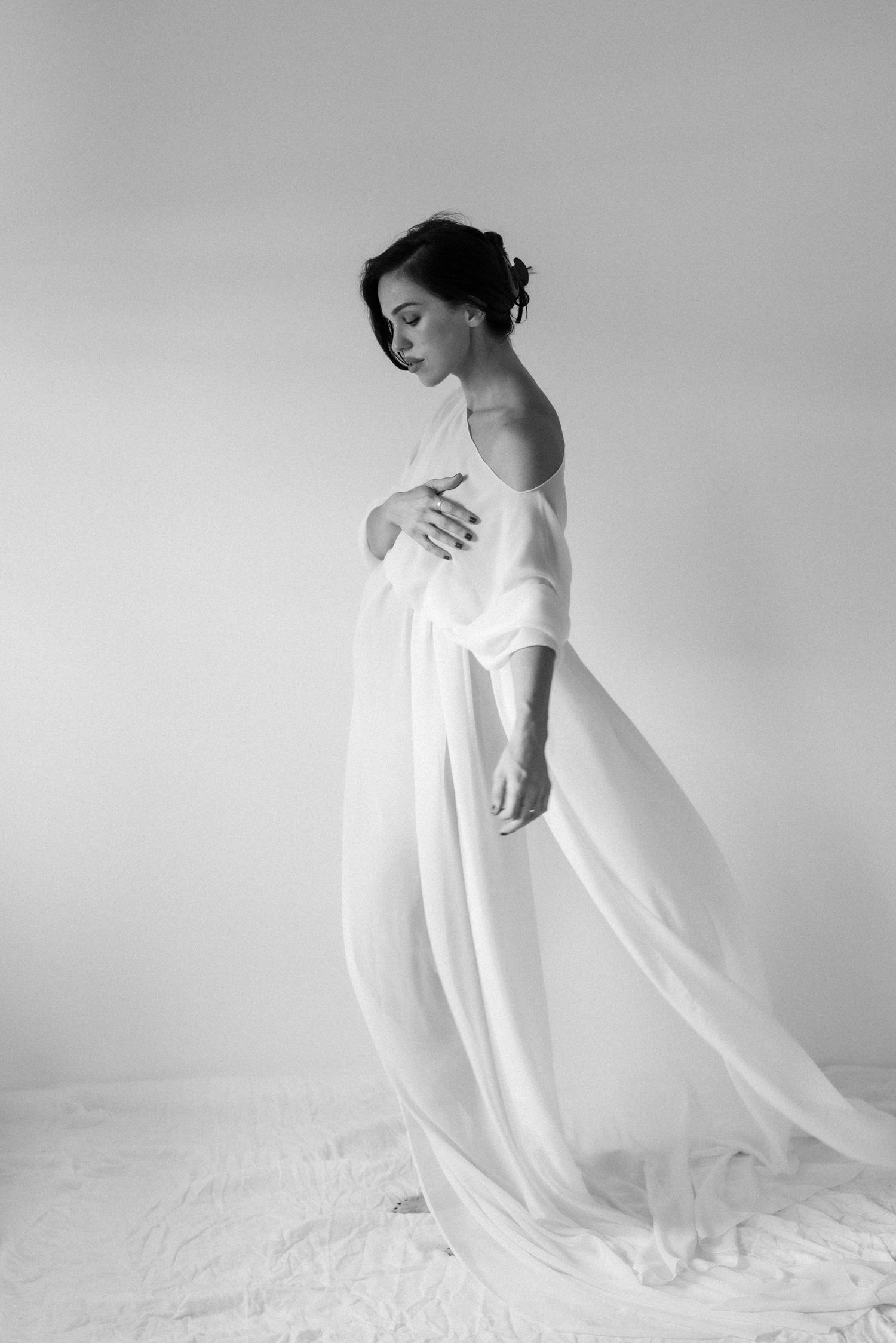 Artistic black and white maternity photos with flowing white fabric creating movement.