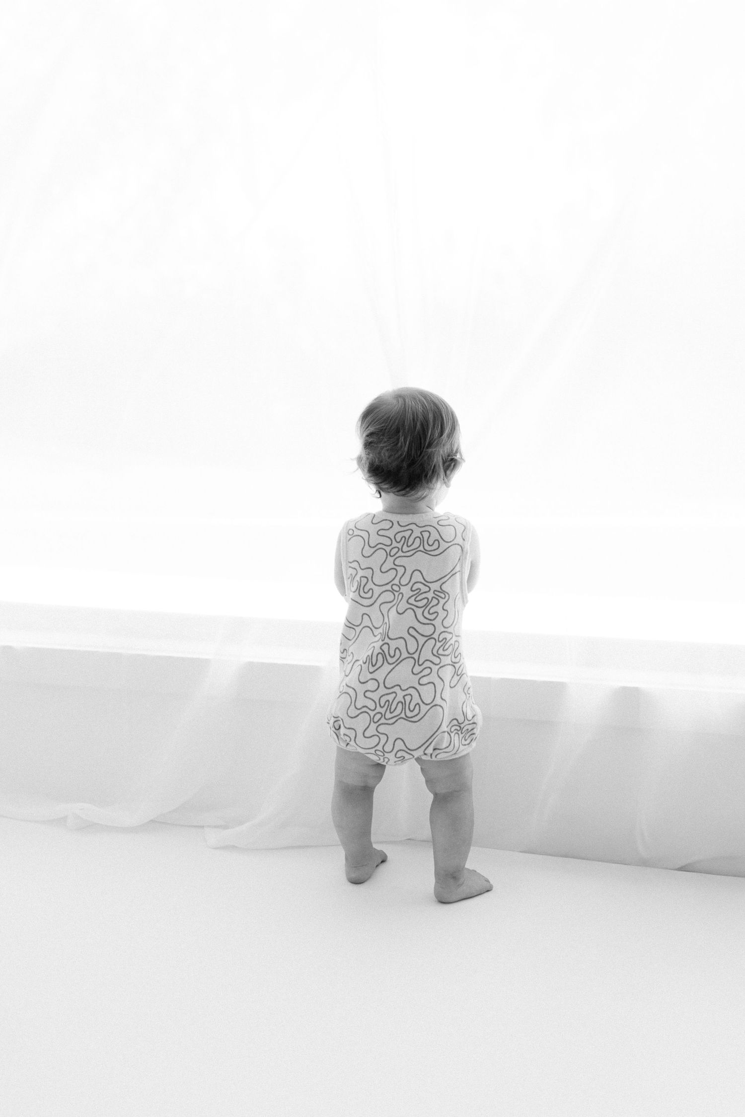 Three sequential images show a baby in patterned pajamas crawling and exploring near a bright window.