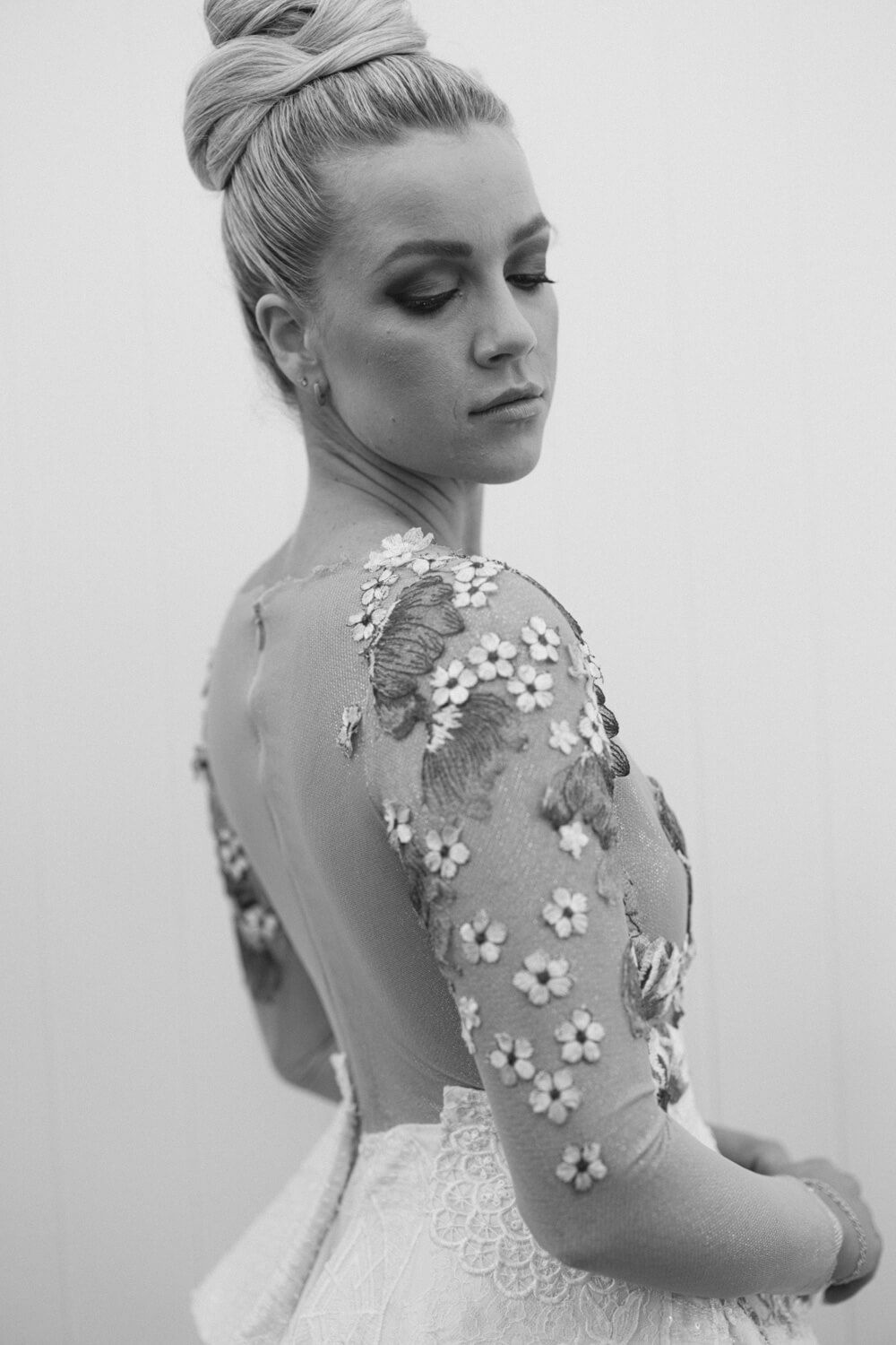 Black and white photo of a woman in a floral embroidered backless wedding gown with an elegant updo hairstyle.