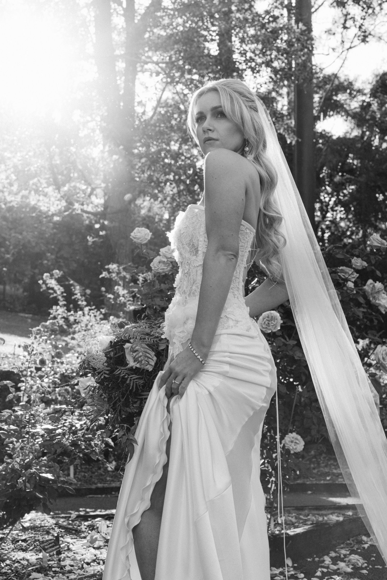 Ethereal bridal portraits in a sunlit garden with flowing white dress and veil.